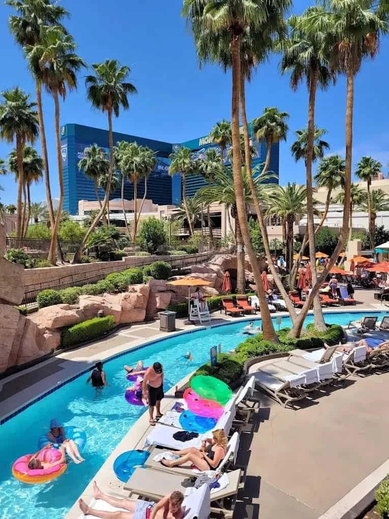 Guests floating on inflatable tubes in MGM Grand's lazy river, palm trees and the MGM Grand tower behind them.