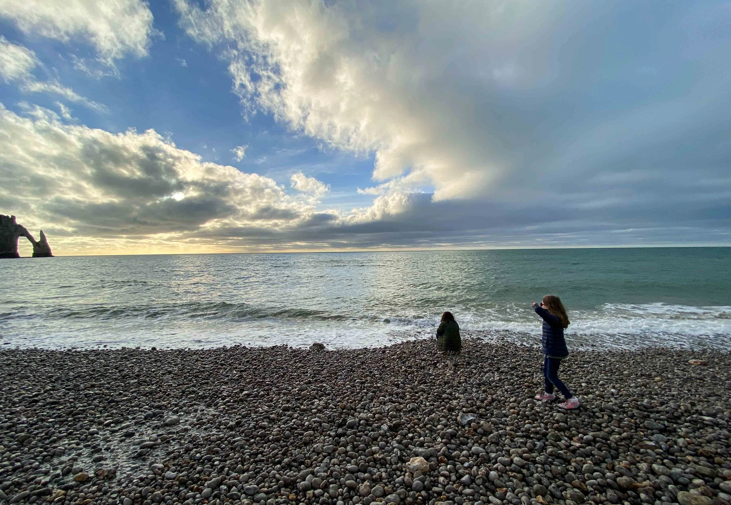 Two young kids exploring the rocky beach of Étretat, France, in the country’s Normandy region