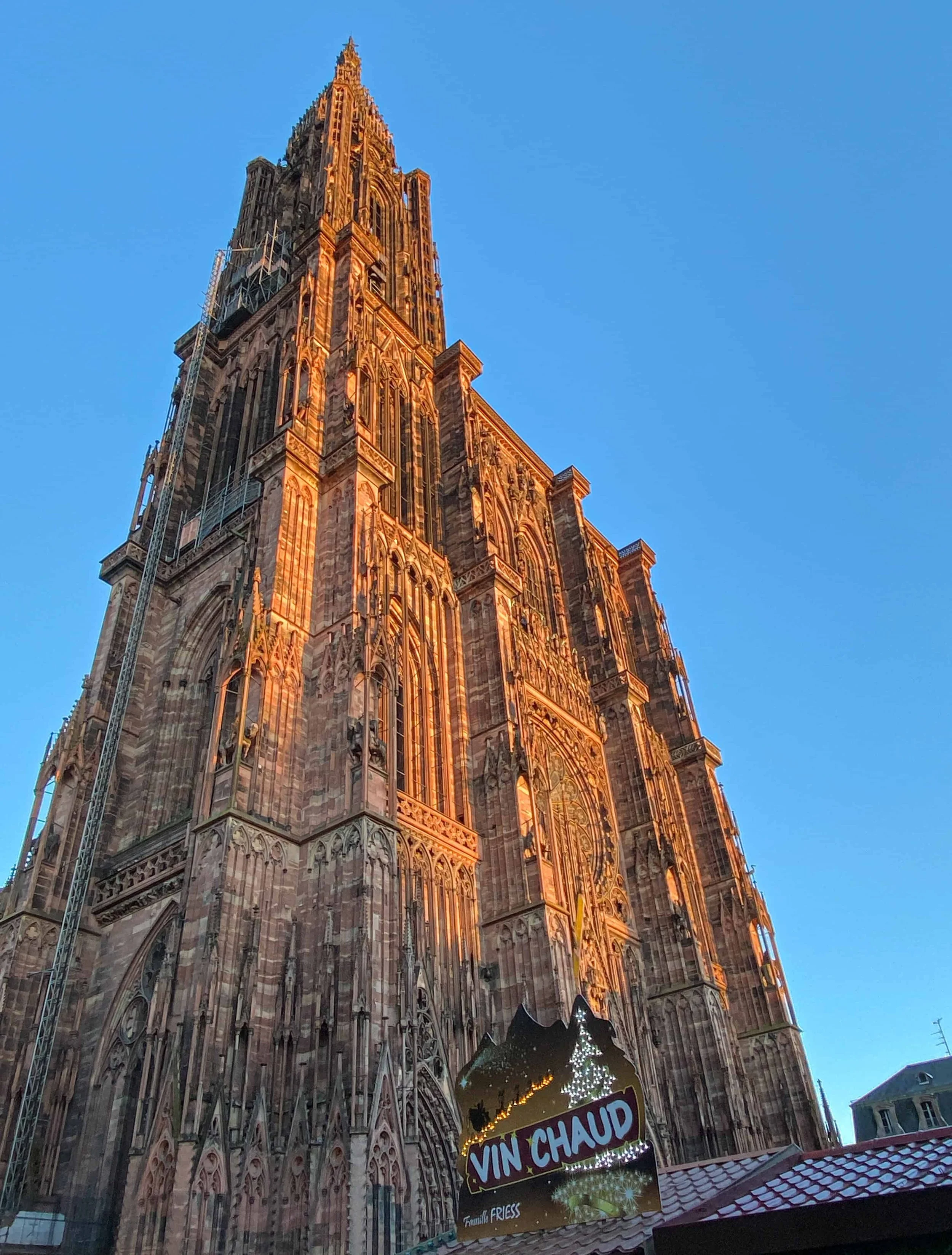 Strasbourg Cathedral spire in golden light above a vin chaud stall at the Christmas market
