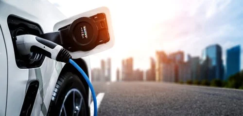 Electric vehicle charging at a city street during sunset