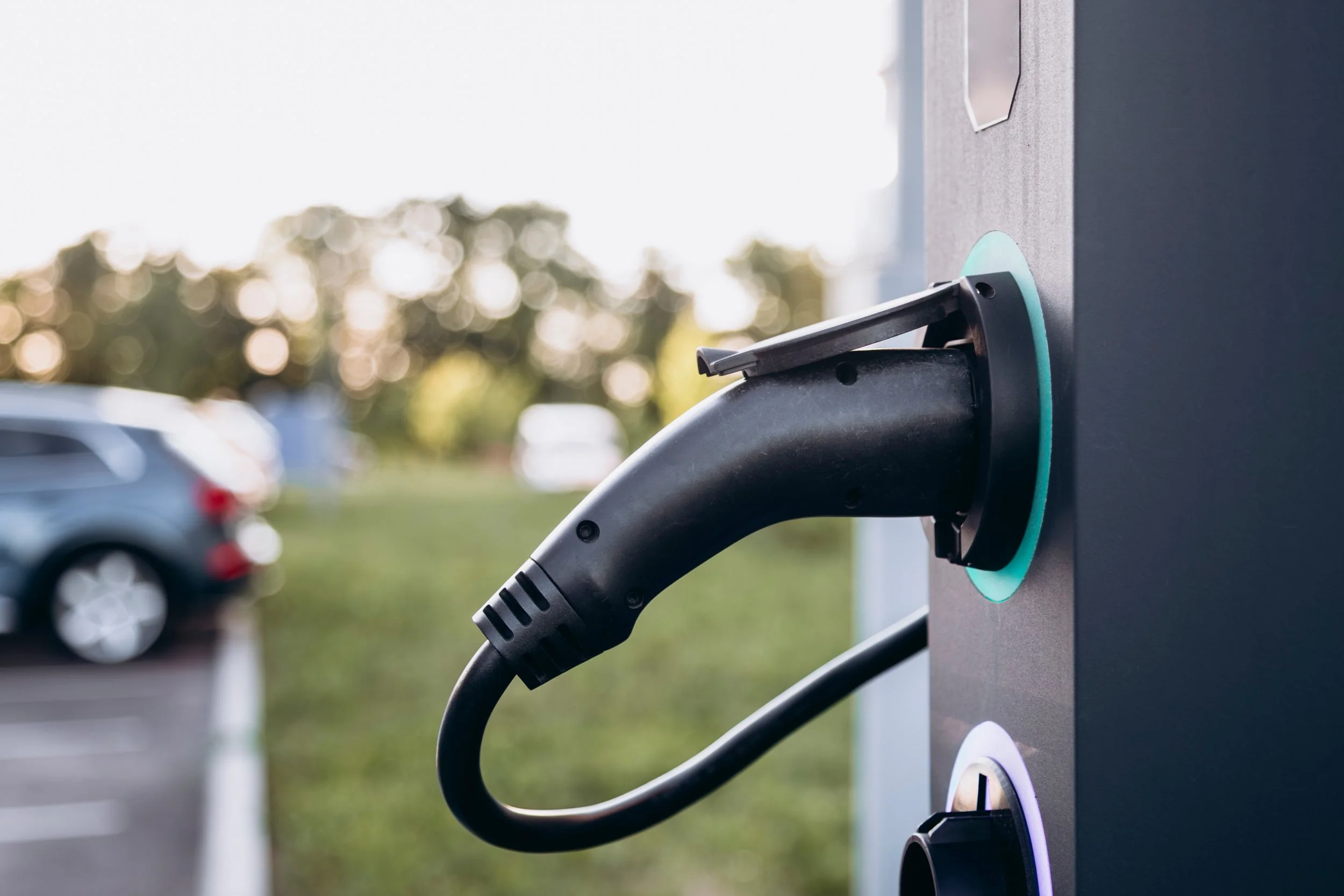 Electric vehicle charging station with charging plug inserted outside in a parking lot during daytime