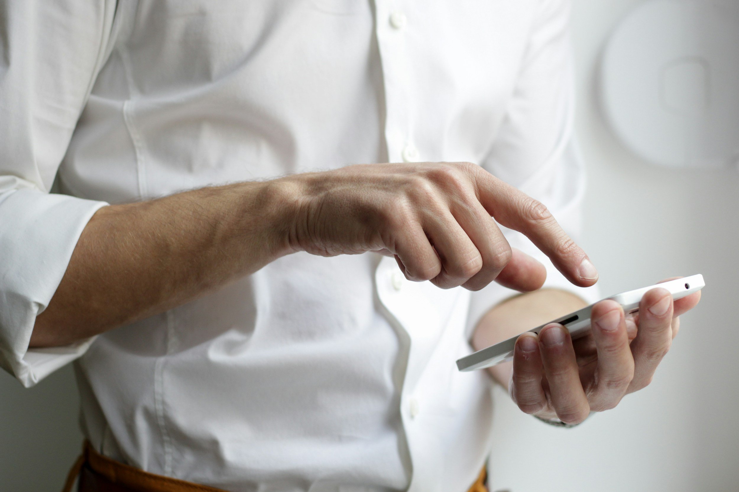 Person in a white shirt holding and using a smartphone.