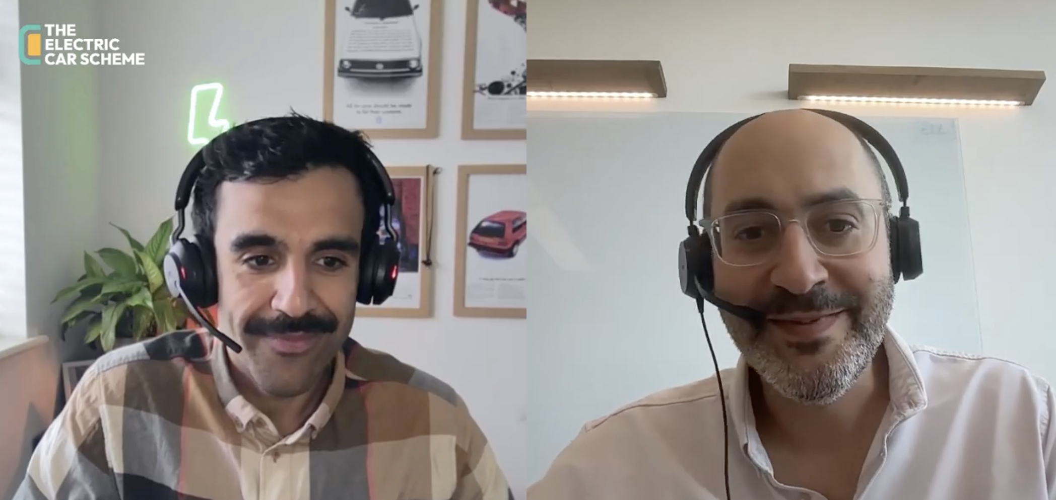 Two men wearing headsets are in a video call or virtual meeting. The man on the left has a mustache, short dark hair, and is wearing a plaid shirt. The background includes framed pictures and a plant. The logo of 'The Electric Car Scheme' appears in the top left corner. The man on the right has glasses, a beard, closely shaved hair, and is wearing a light-colored shirt with a whiteboard and ceiling lights in the background.