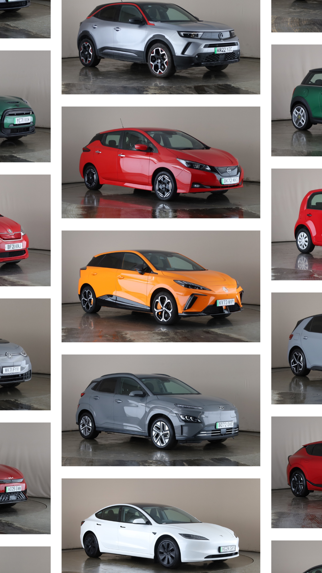 Collection of various modern cars including a silver compact SUV, a red hatchback, an orange compact car, a gray electric SUV, a white sedan, and other small vehicles, all parked indoors.