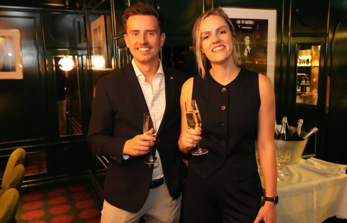 A man and woman in formal attire holding glasses of champagne at a celebration or party.