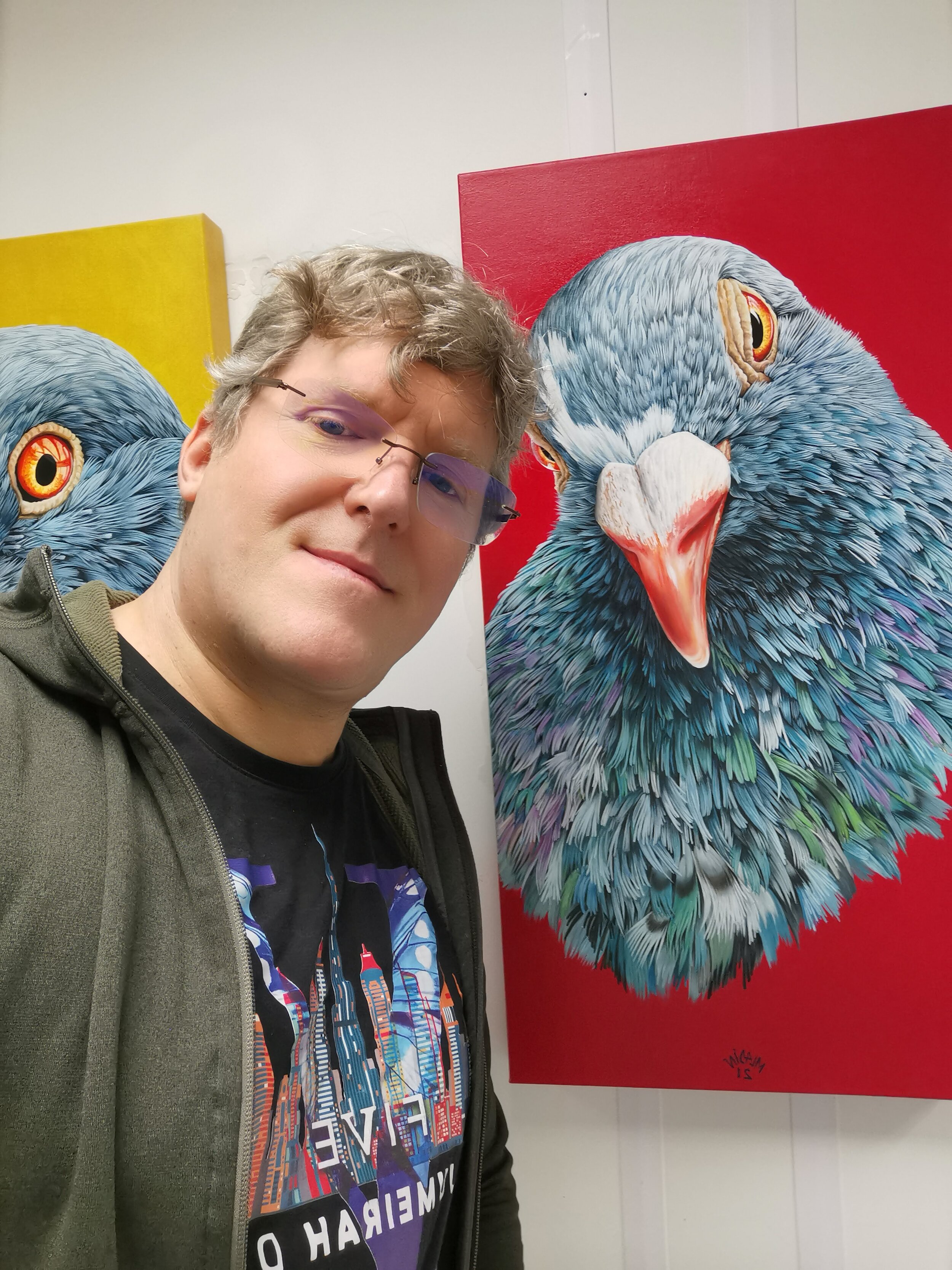 Person taking a selfie with colorful pigeon paintings in the background