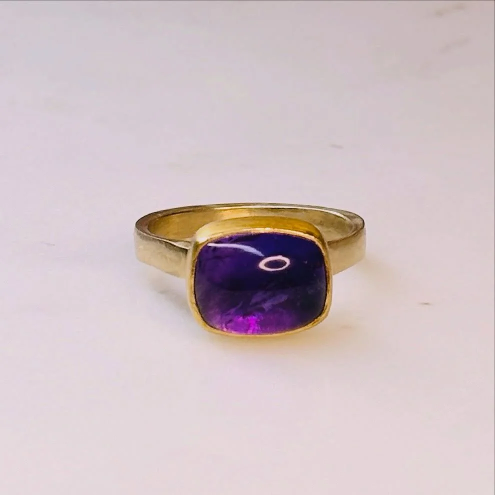 This stunning amethyst ring features a radiant gemstone set in a 22 karat gold bezel atop a 14 karat gold signet band. The amethyst glows beautifully from within, revealing captivating hues of pinks and purples that shift with the light. Elegant yet