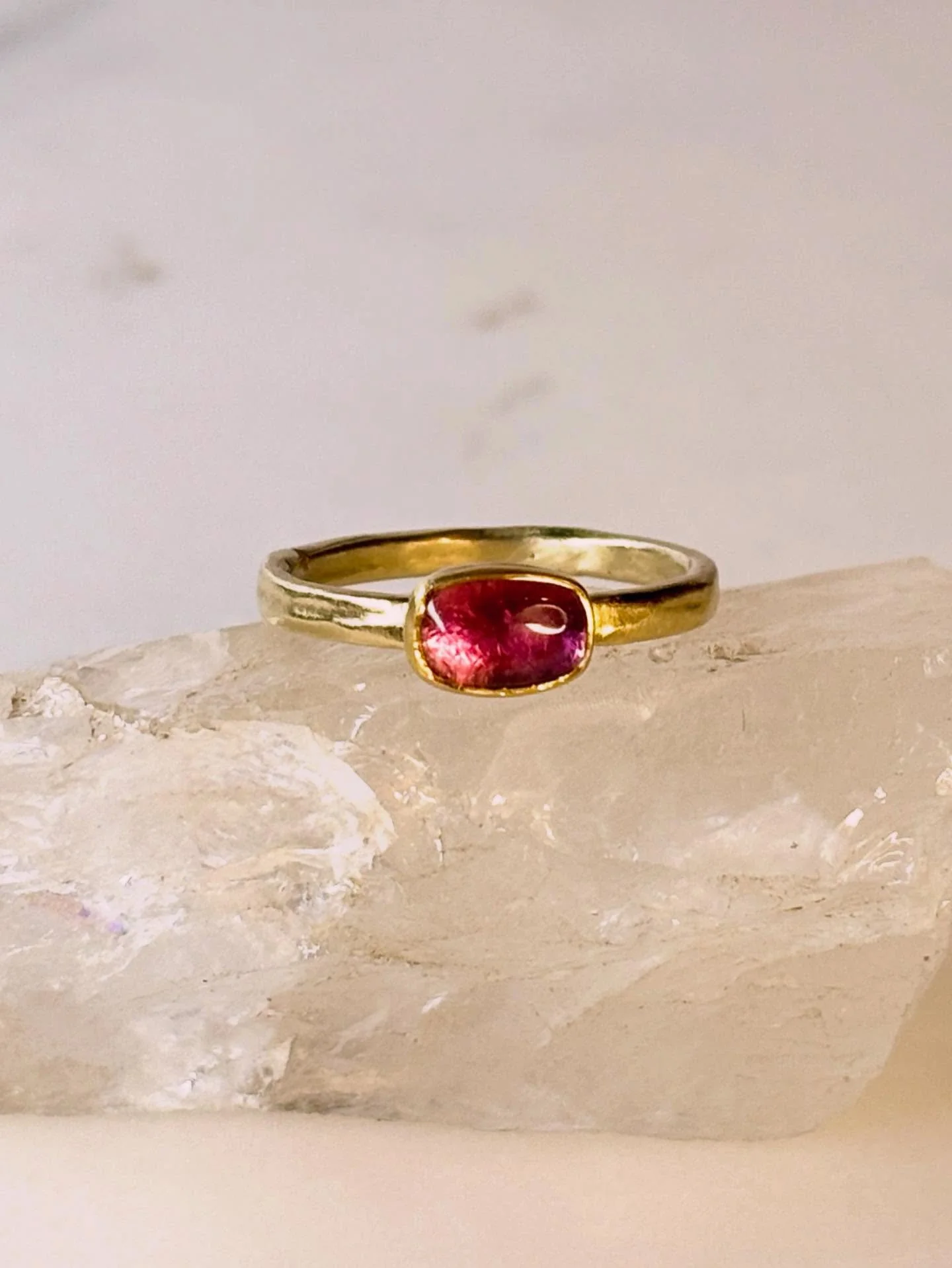 A petite rectangular pink tourmaline radiates a soft, luminous glow, set in a rich 22k gold bezel on a 18k gold band. Its refined simplicity makes it perfect on its own or stacked with other rings for a touch of warm, elegant color.