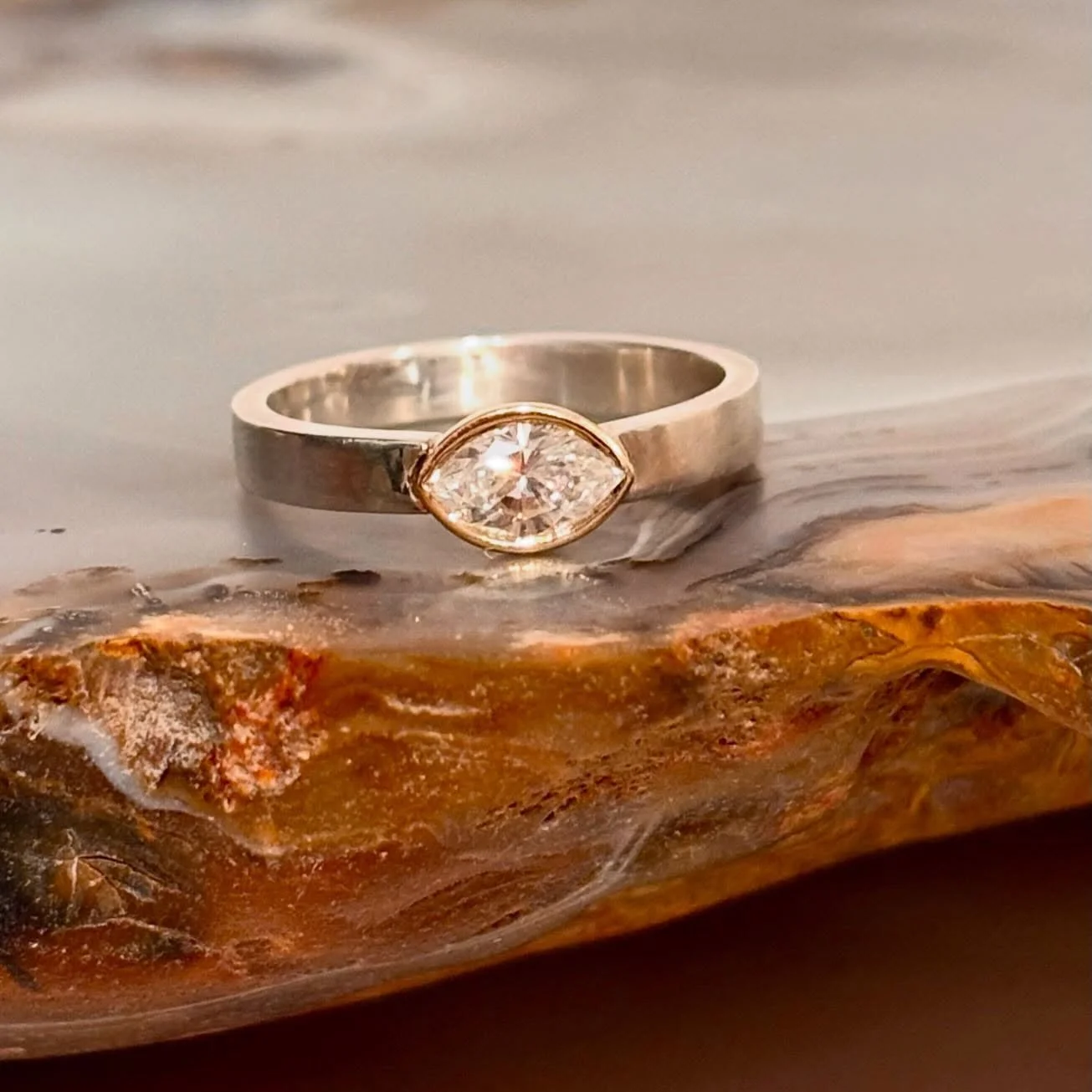 A marquise diamond with its graceful, elongated silhouette brings a sense of quiet sophistication to this piece. Set in a warm gold bezel, the stone feels both protected and softly illuminated, while the contrasting silver band adds a modern edge. Th