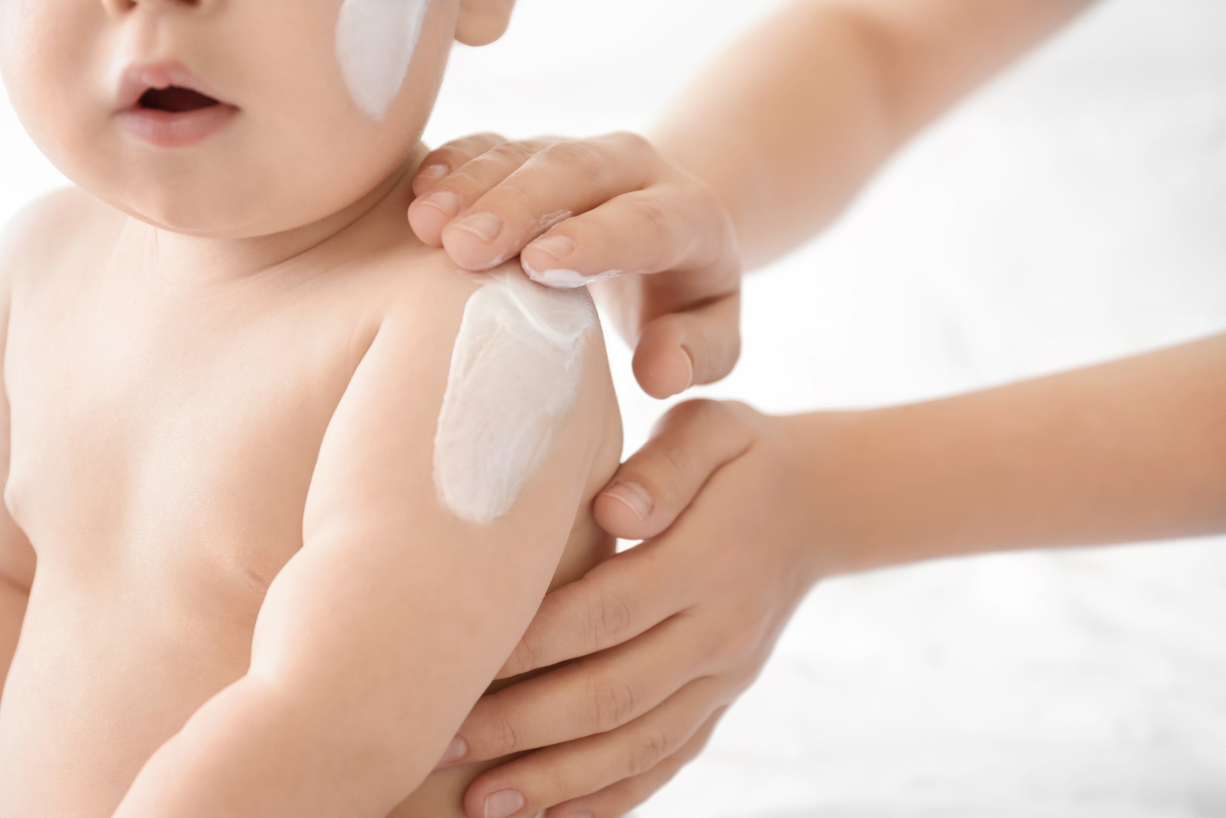 Parent applying lotion to a baby