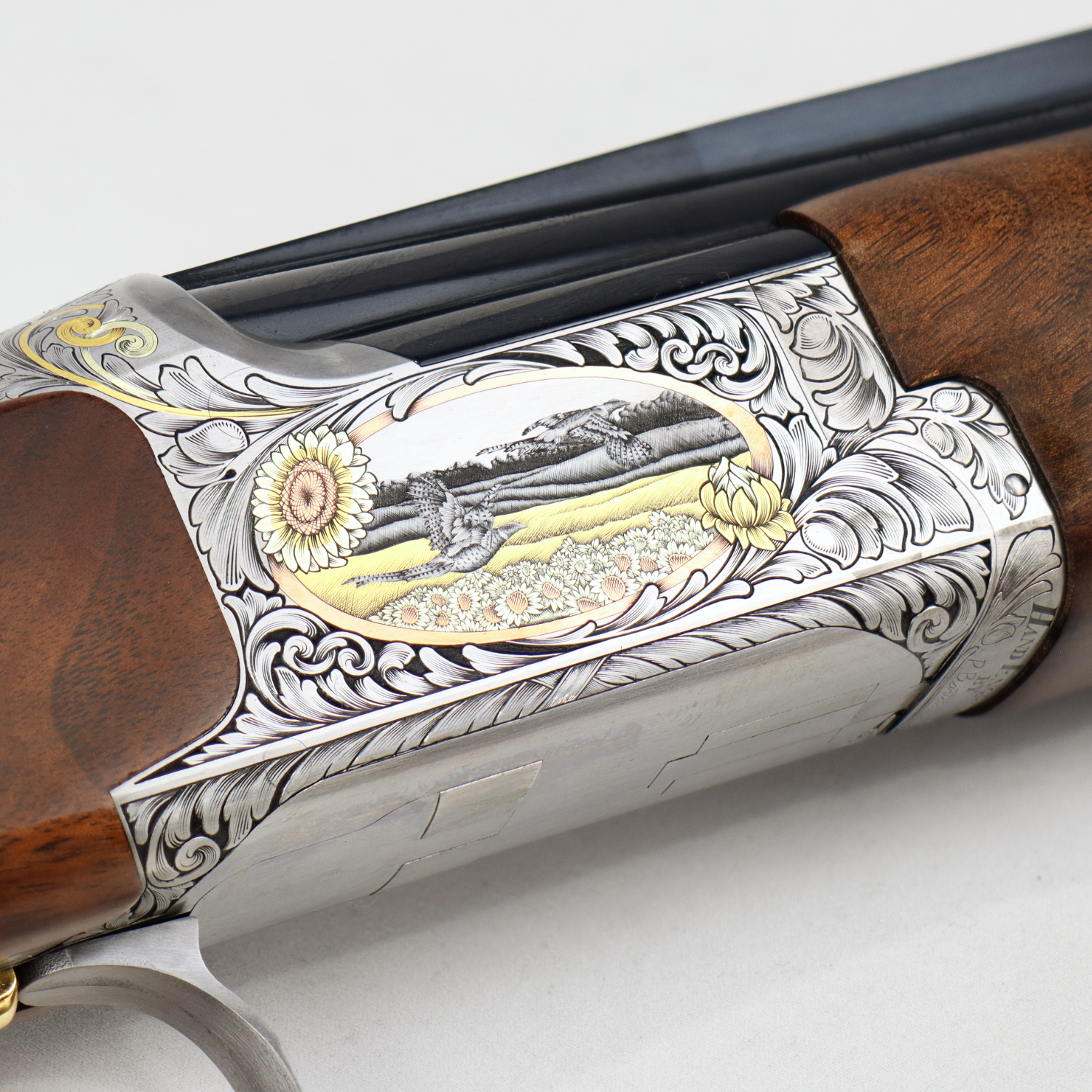 close up of an engraved gun showing birds flying in a field.