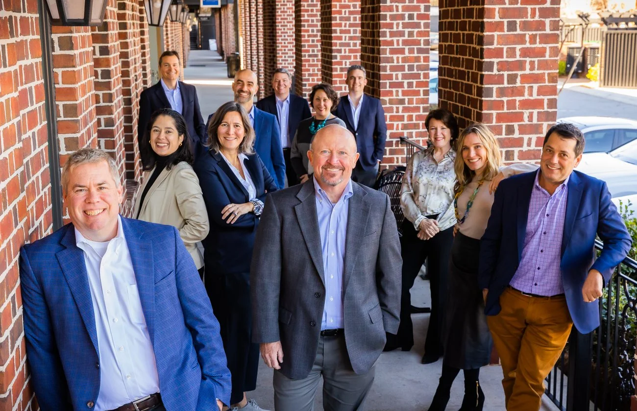 Group of professionals standing outside a brick building, smiling for a photo.