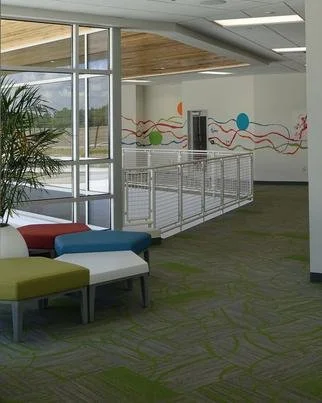 Indoor recreational or waiting area with colorful benches, large window, wall mural, and a water fountain.