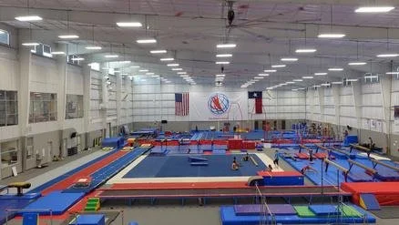 Interior of an Olympic gymnastics training facility with various mats, balance beams, and gymnastic equipment.