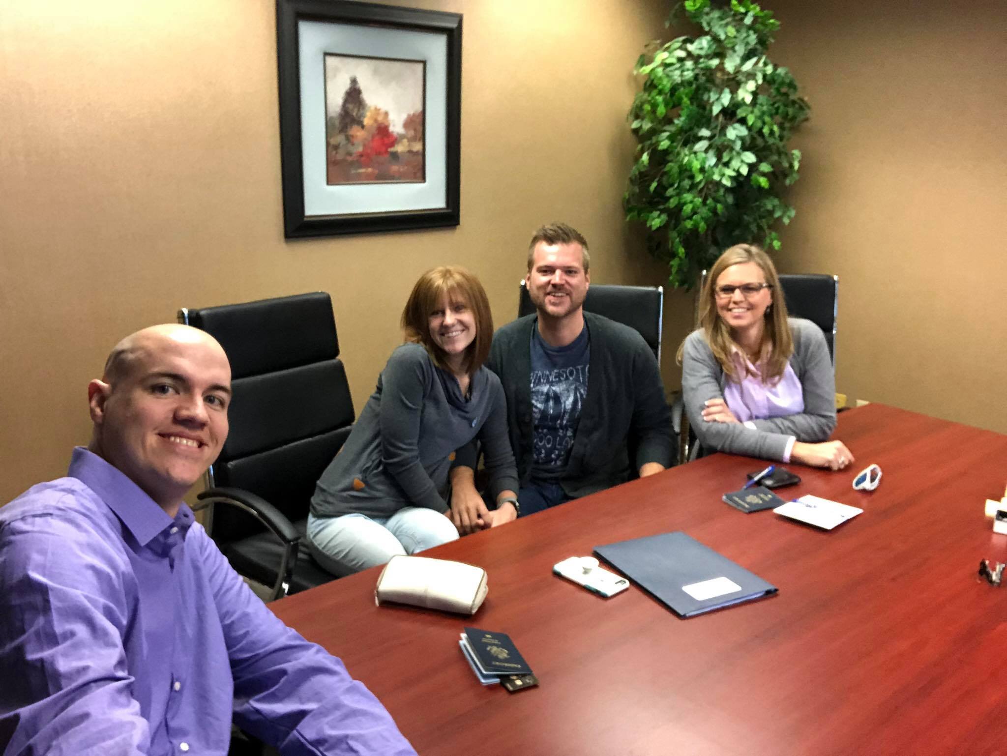 Four people around table, smiling.
