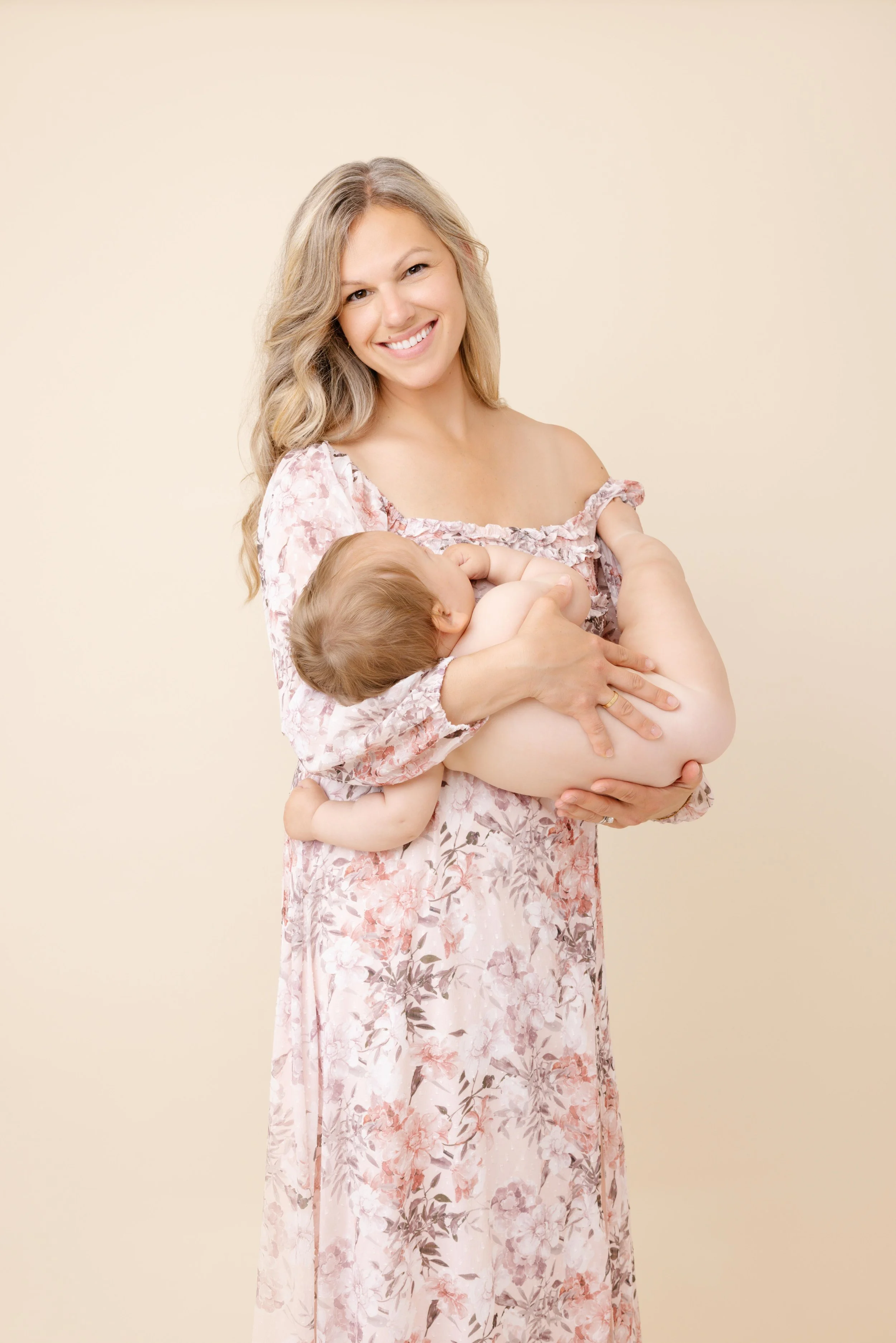 maman qui tient son bébé pour séance photo en studio avec fond beige