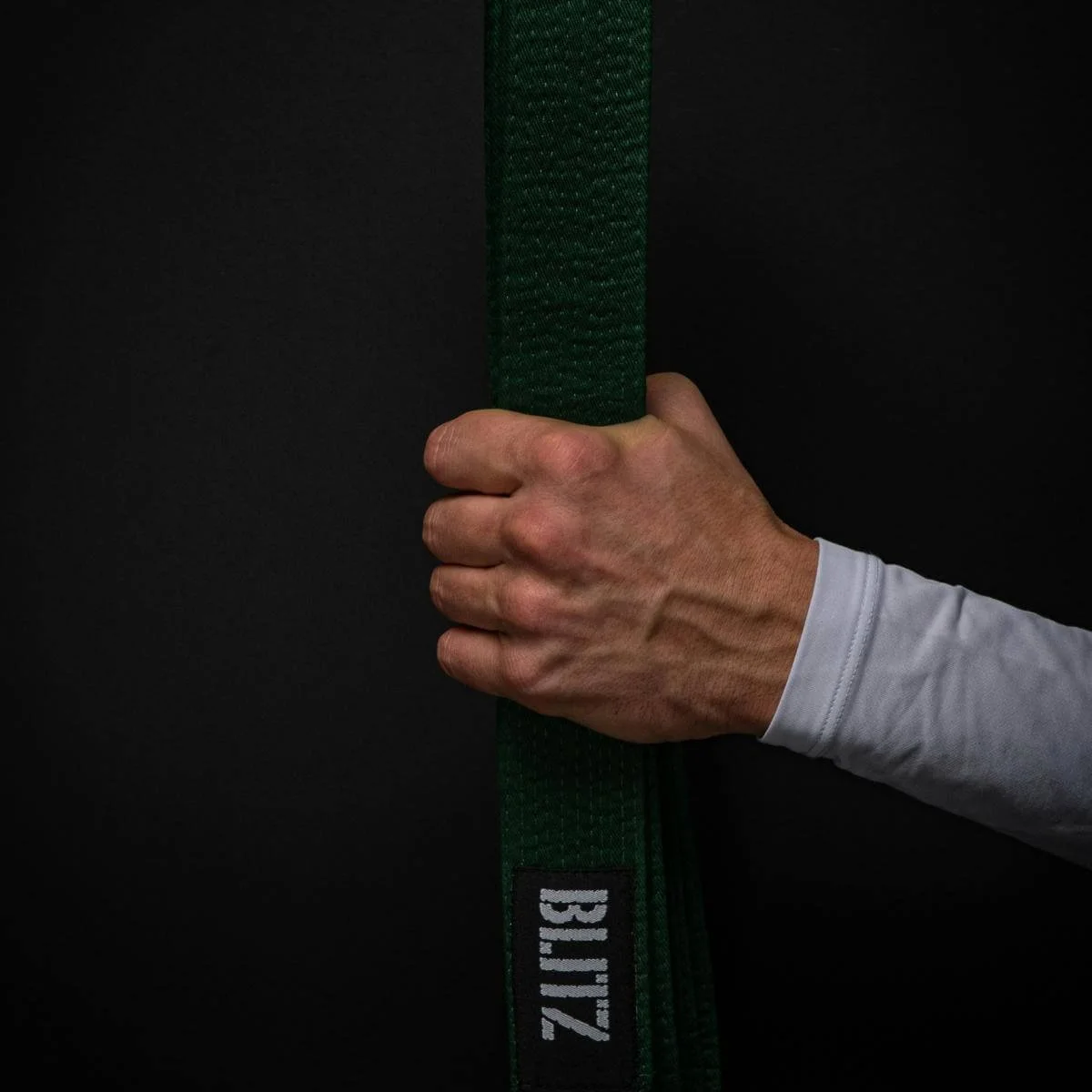a man's hand holding a karate black belt