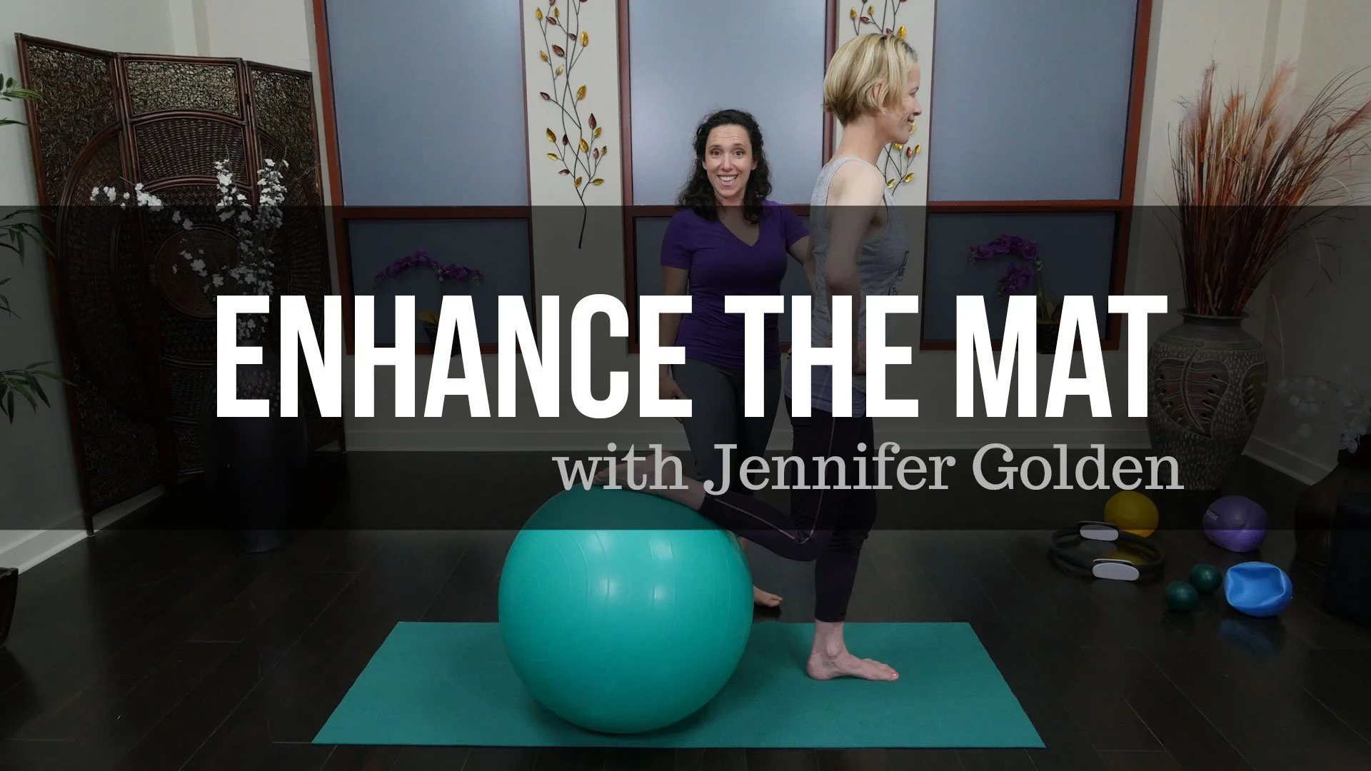 Two women posing in a studio with a large exercise ball, yoga mats, and various workout equipment. The background has decorative wall art and plants. The image promotes a workshop called 'Enhance the Mat with Jennifer Golden'.