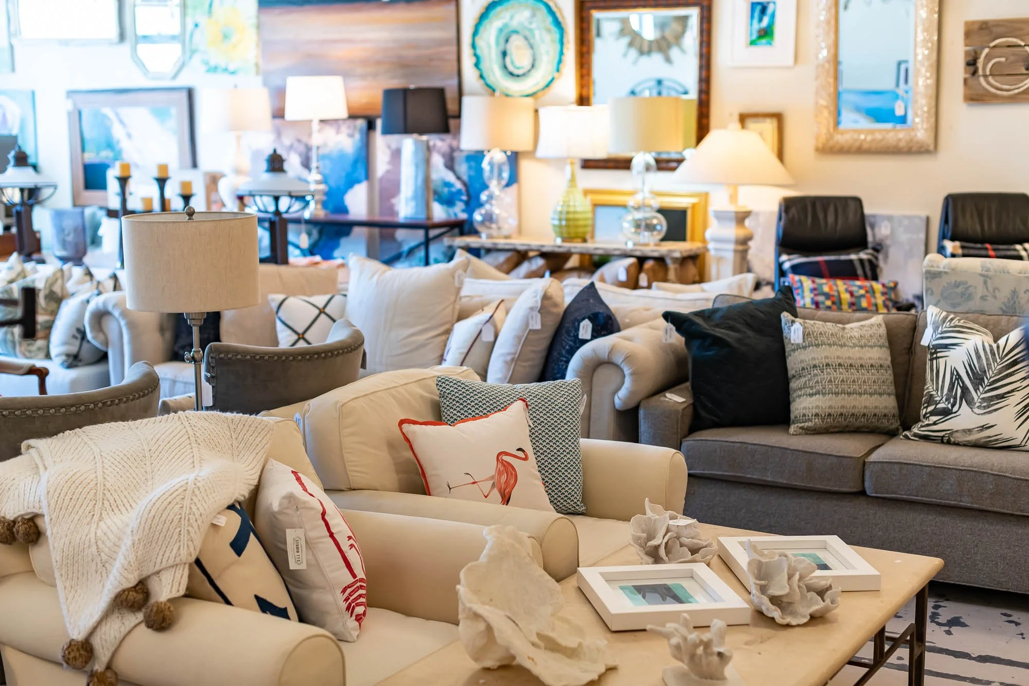 A furniture store displays various sofas, armchairs, and tables decorated with pillows, lamps, and artwork.