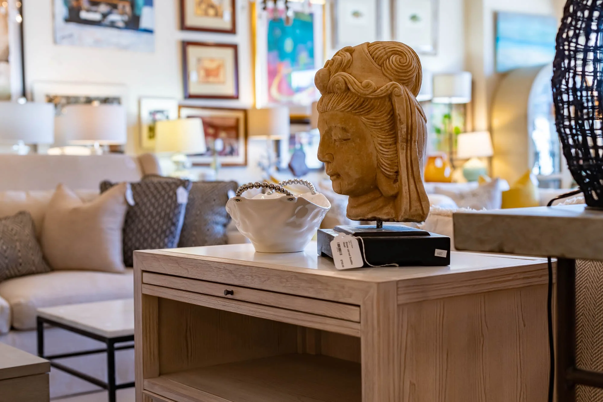 Decorative wooden bust sculpture of a woman's profile on a wooden table in a bright living room.