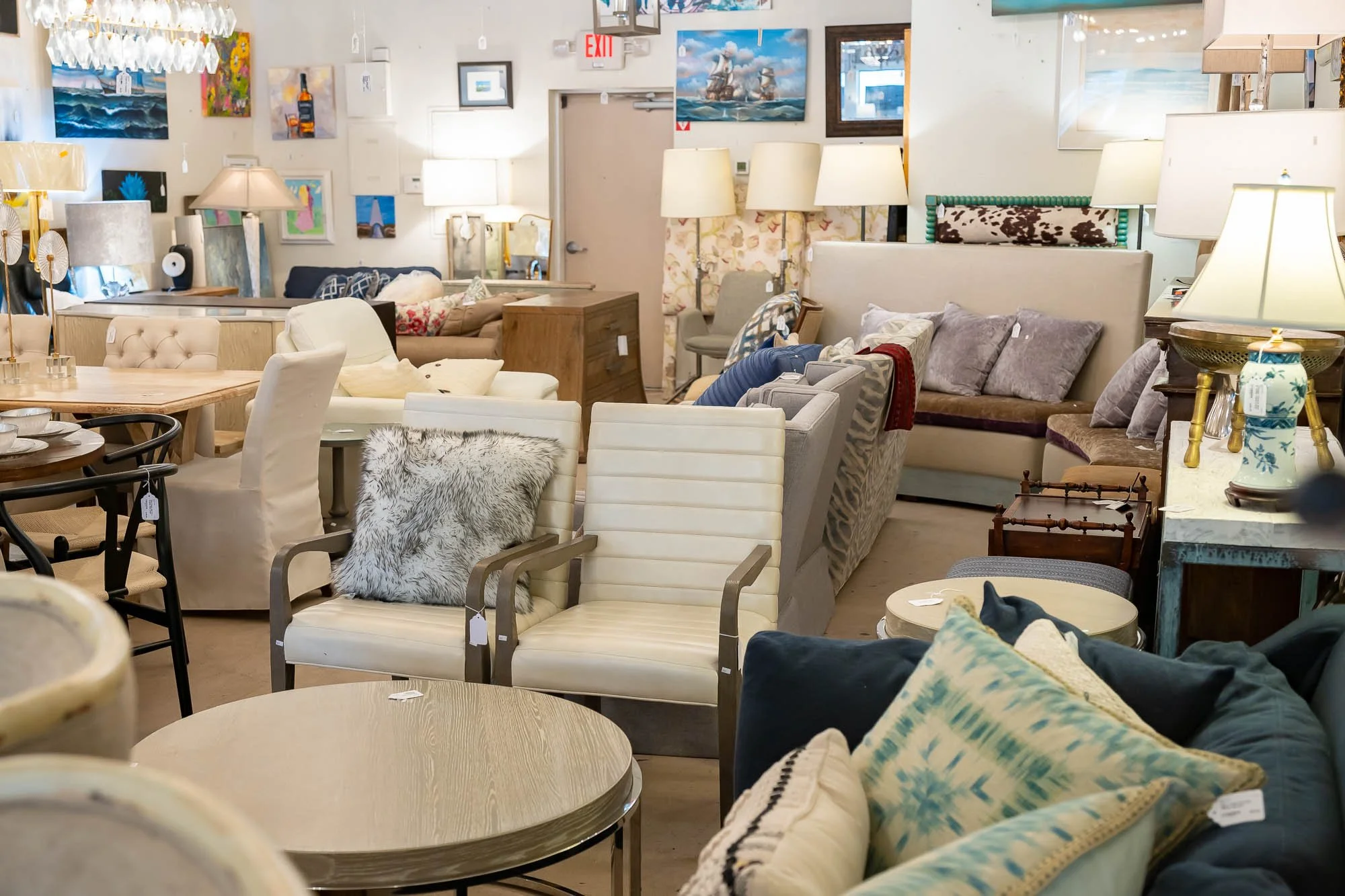Furniture display in a store, including sofas, armchairs, lamps, and wall art.