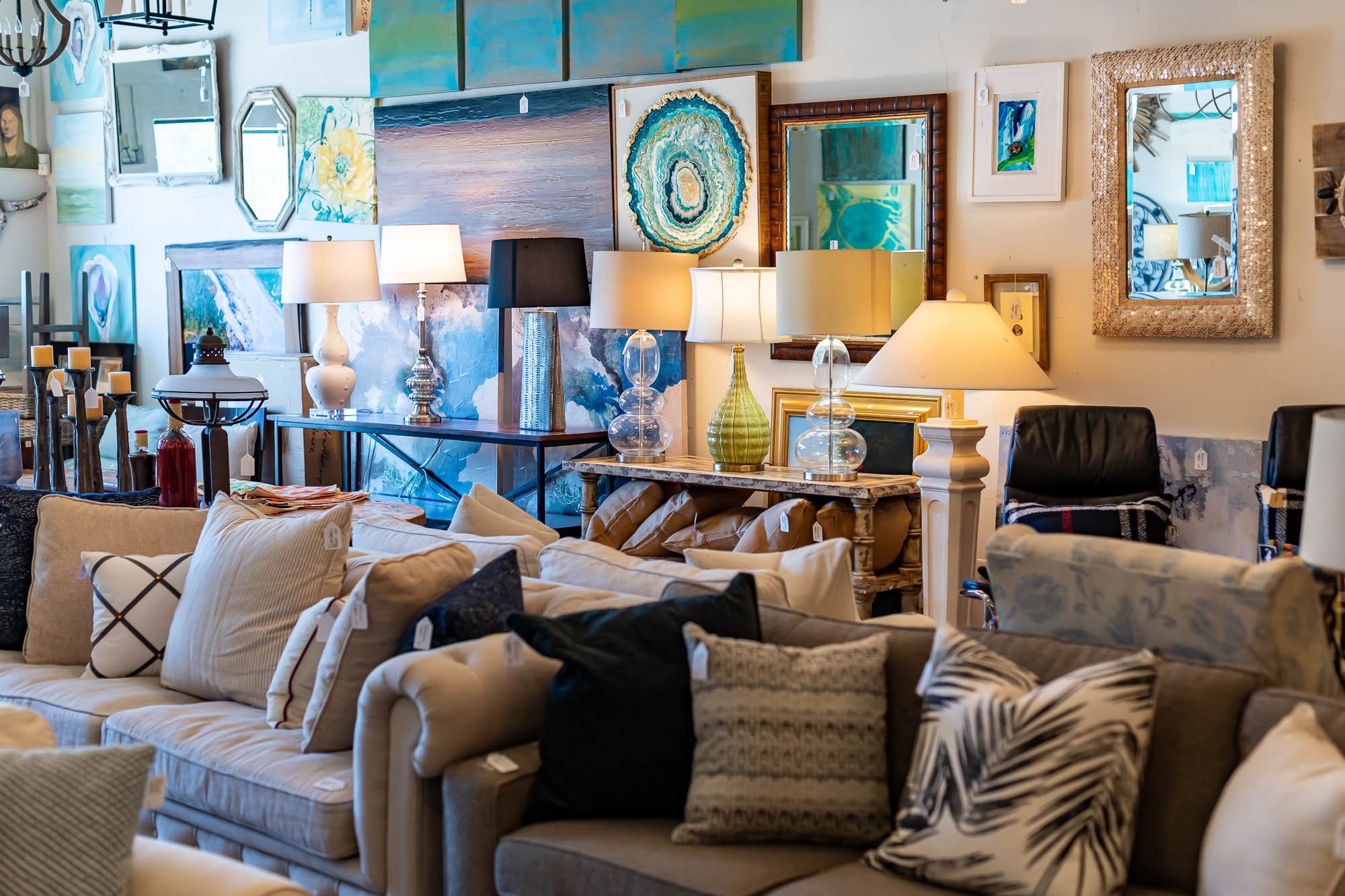 Furniture store display with couches, lamps, framed artwork, and decorative mirrors.