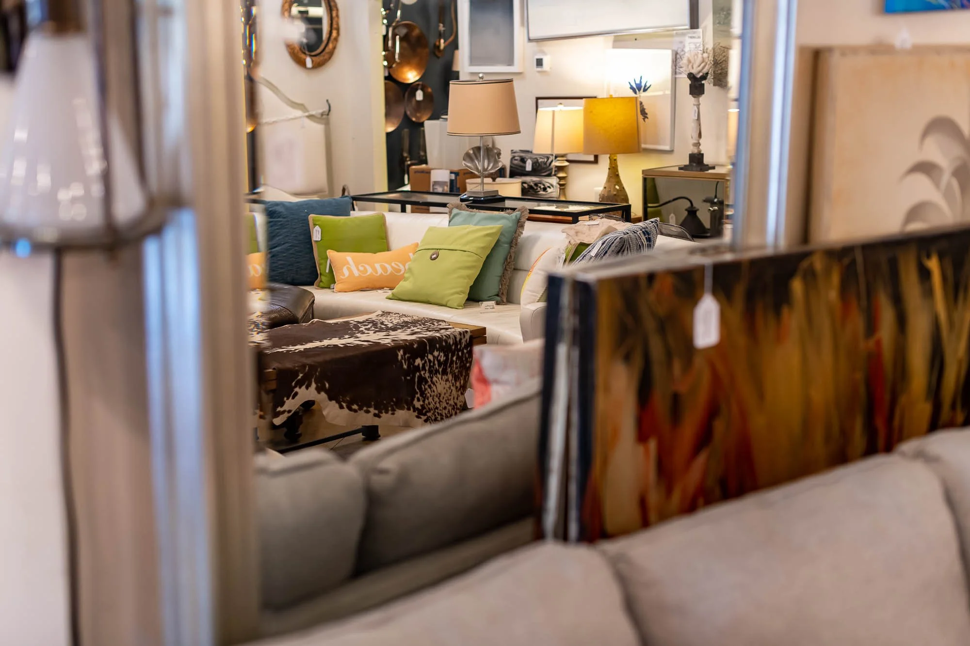 A furniture store displays various sofas, coffee tables, and lamps, viewed through a mirror reflection.