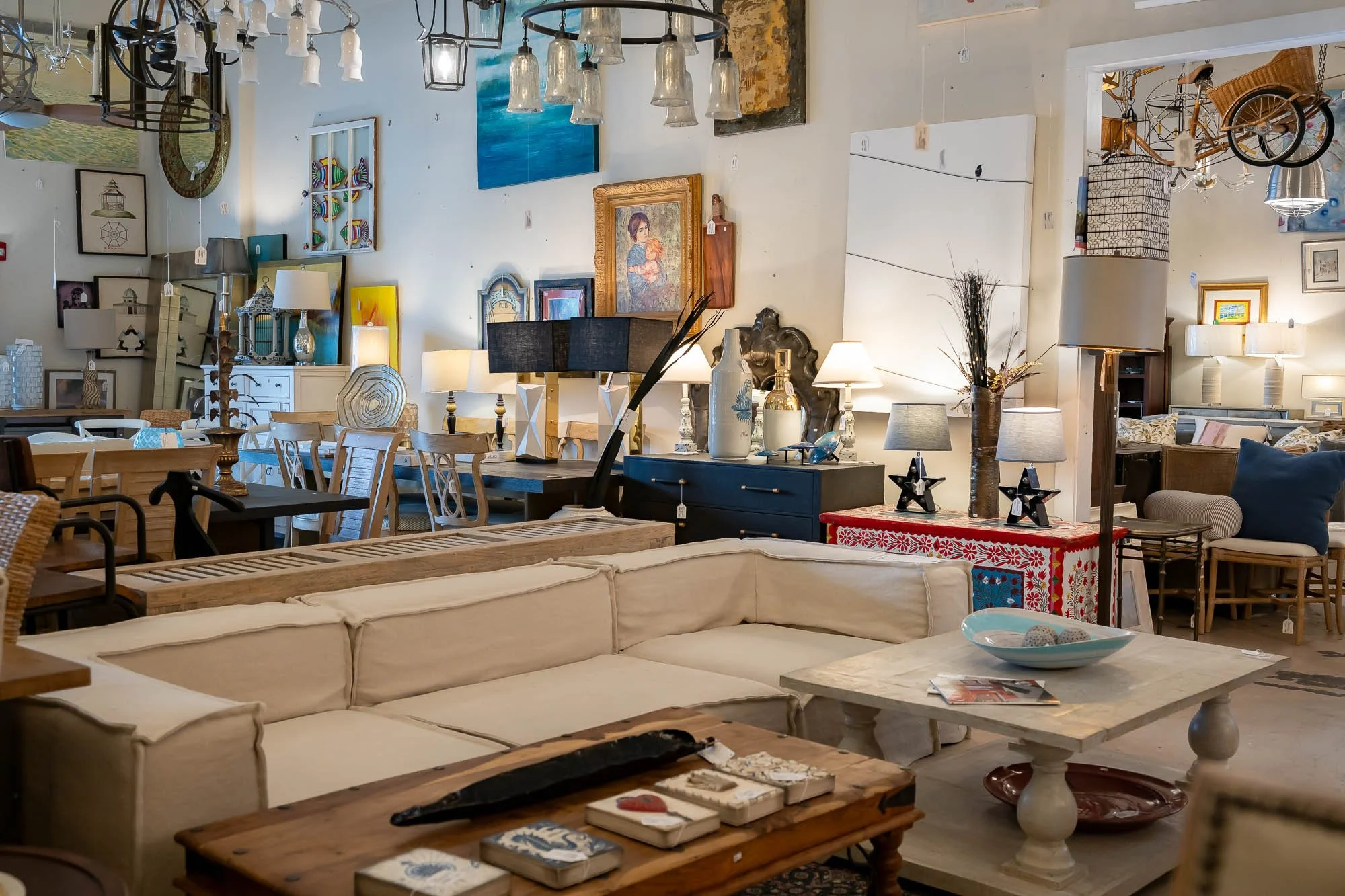Interior of a furniture store showcasing various sofas, tables, lamps, and wall art.