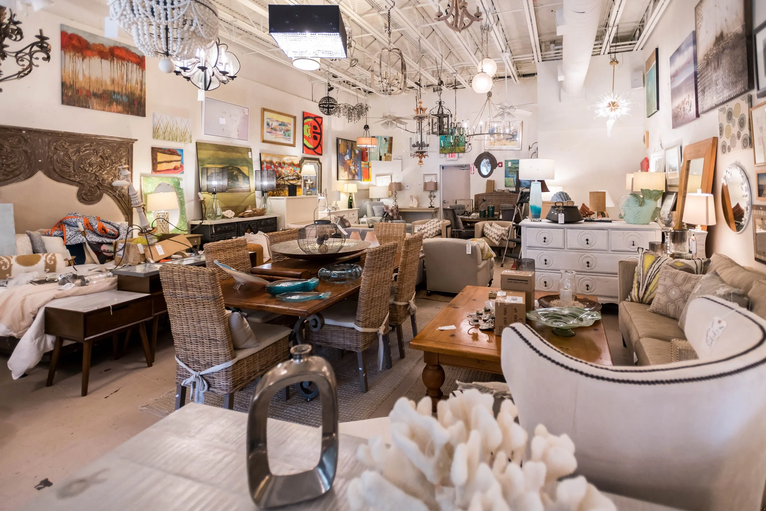 Interior of a furniture store displaying various sofas, chairs, tables, lamps, and art decorations.