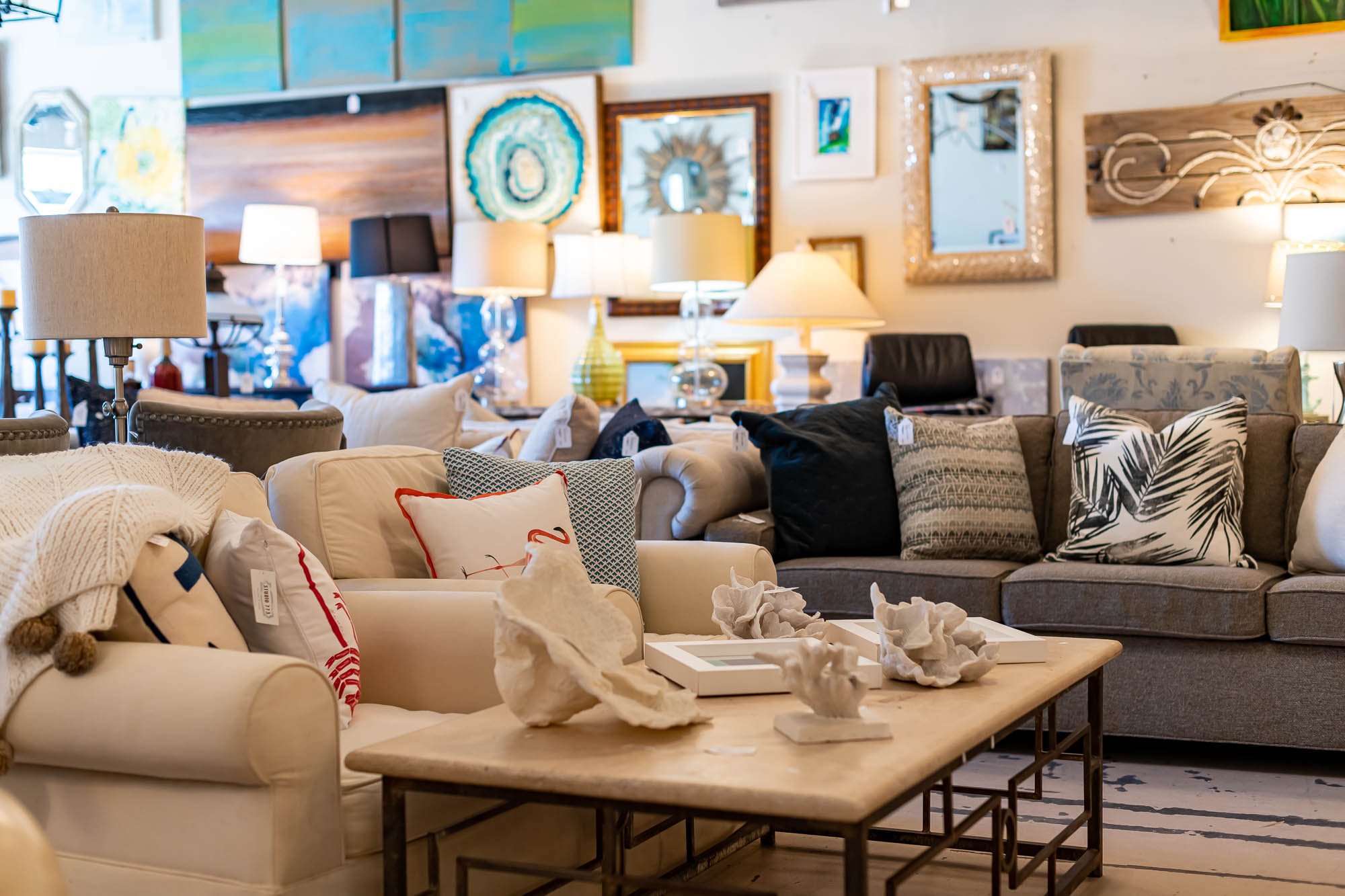 A furniture store display with various sofas, decorative pillows, chairs, lamps, and wall art.