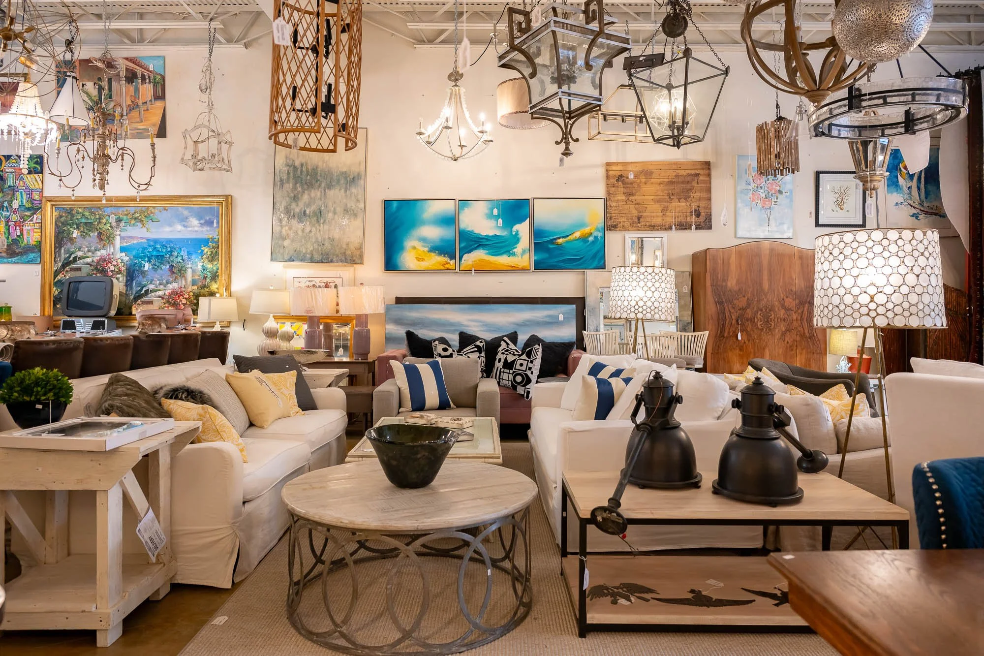 A furniture showroom displaying various sofas, lamps, and wall art in a spacious, well-lit setting.