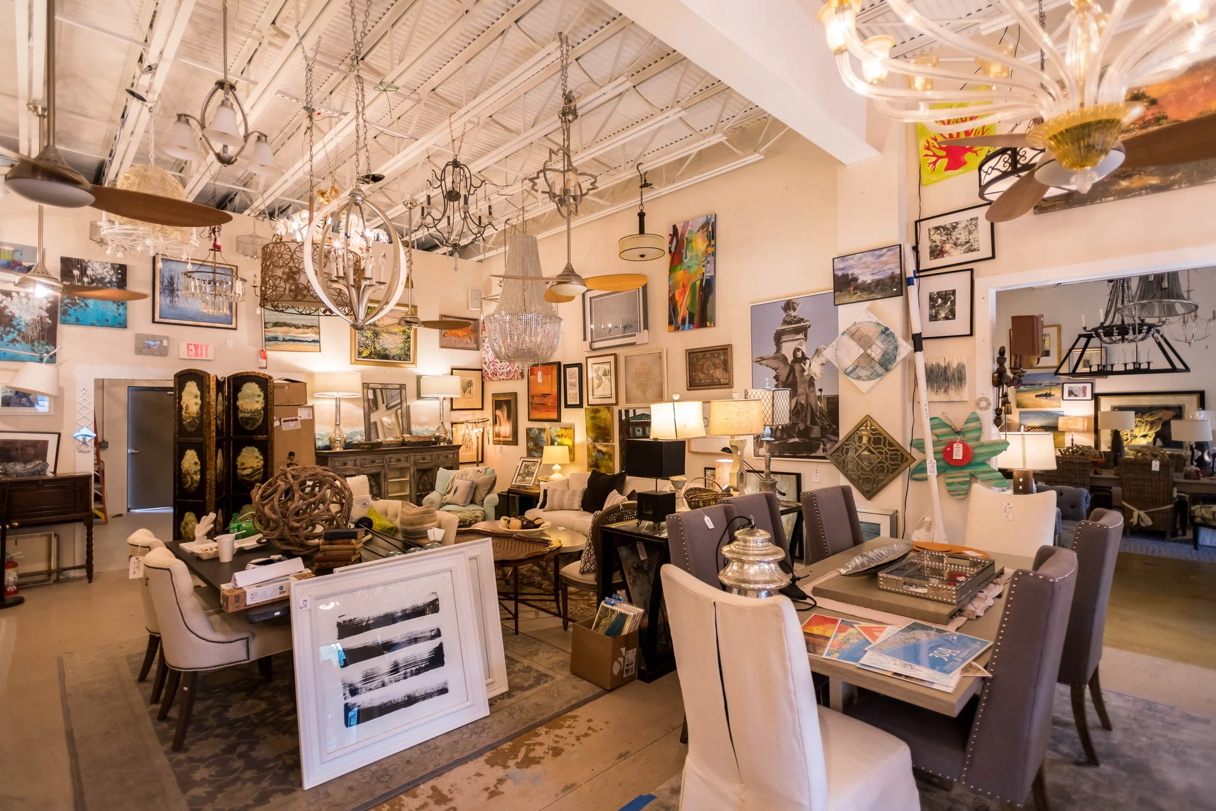 Interior of an antique shop with various furniture, lamps, and artwork on the walls.