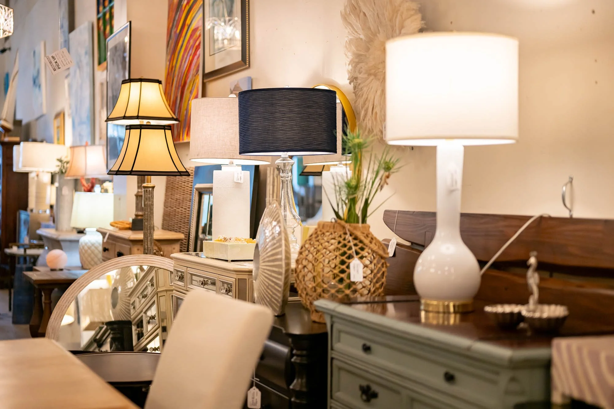 Various table lamps on a sideboard and a table in a furniture store.