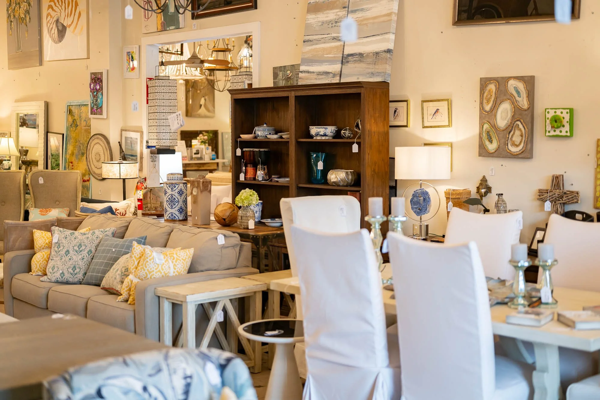 Interior of a furniture store displaying sofas, dining chairs, lamps, shelves, and various decorative items.