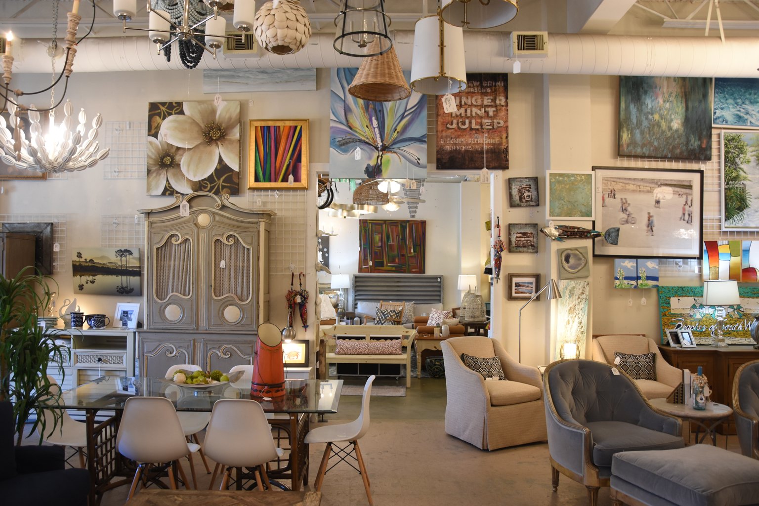 Interior of an art and furniture store with various paintings, lamps, and furniture pieces.
