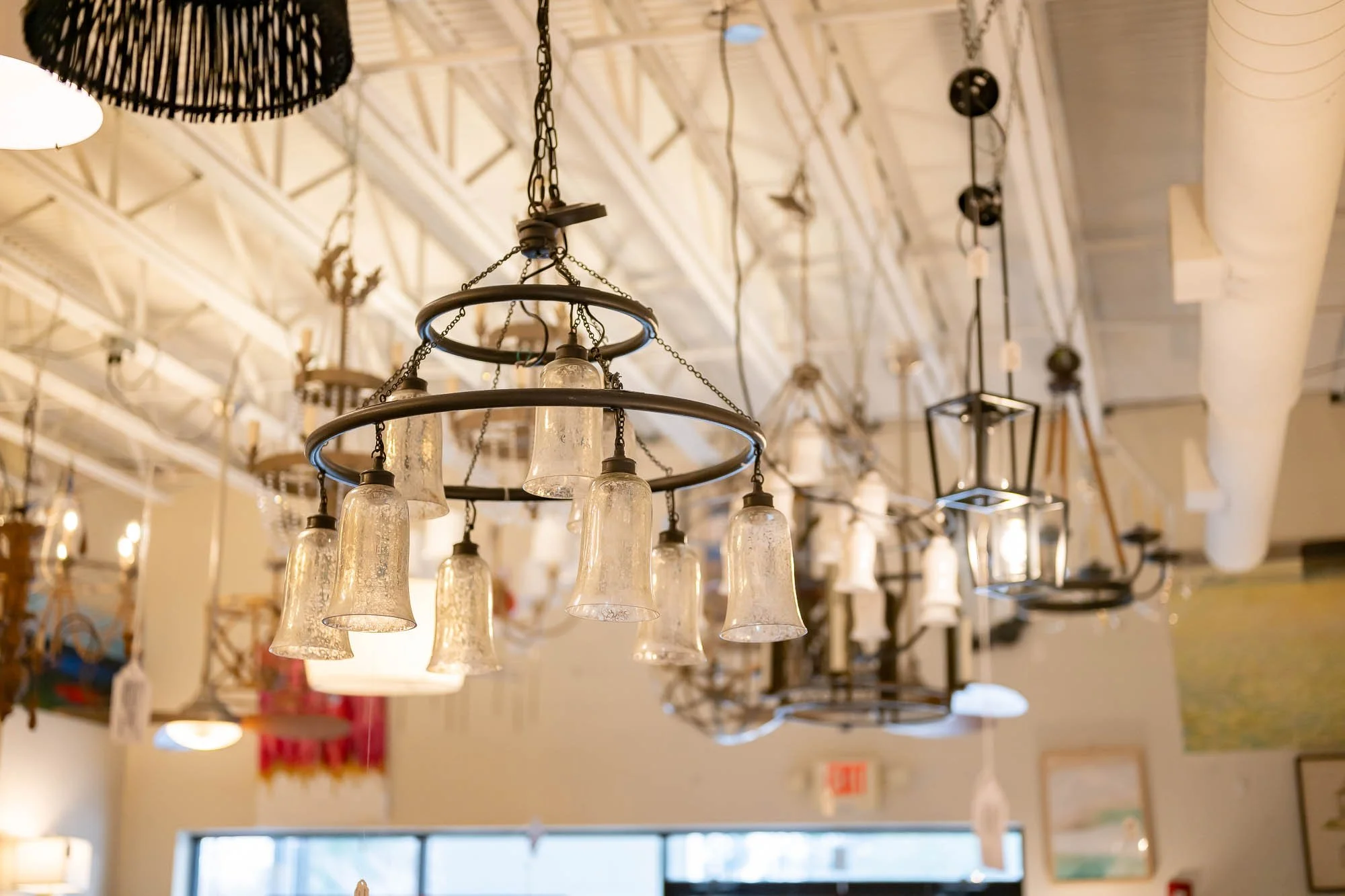A chandelier with multiple glass lampshades hanging from chains in a lighting store.