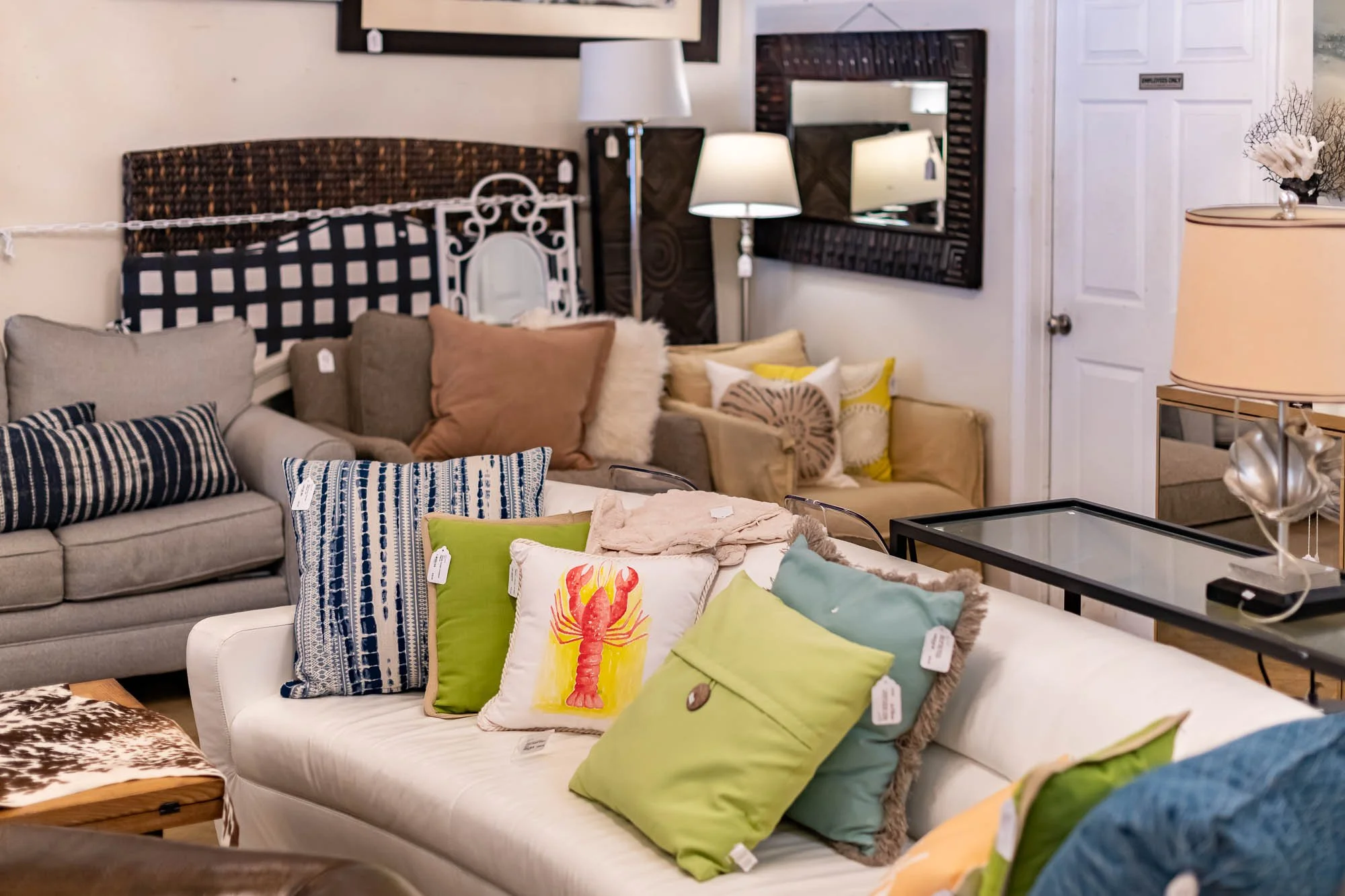 A furniture store display with various sofas, cushions, and lamps in a showroom setting.