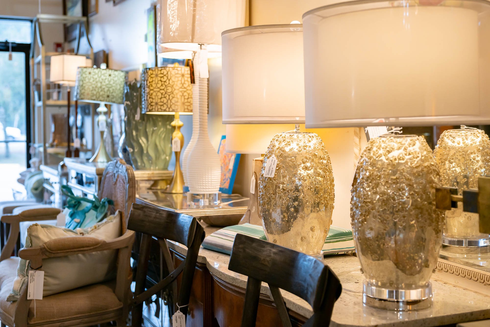 A display of various table lamps on a countertop, with different shapes, colors, and designs, in a home decor store.