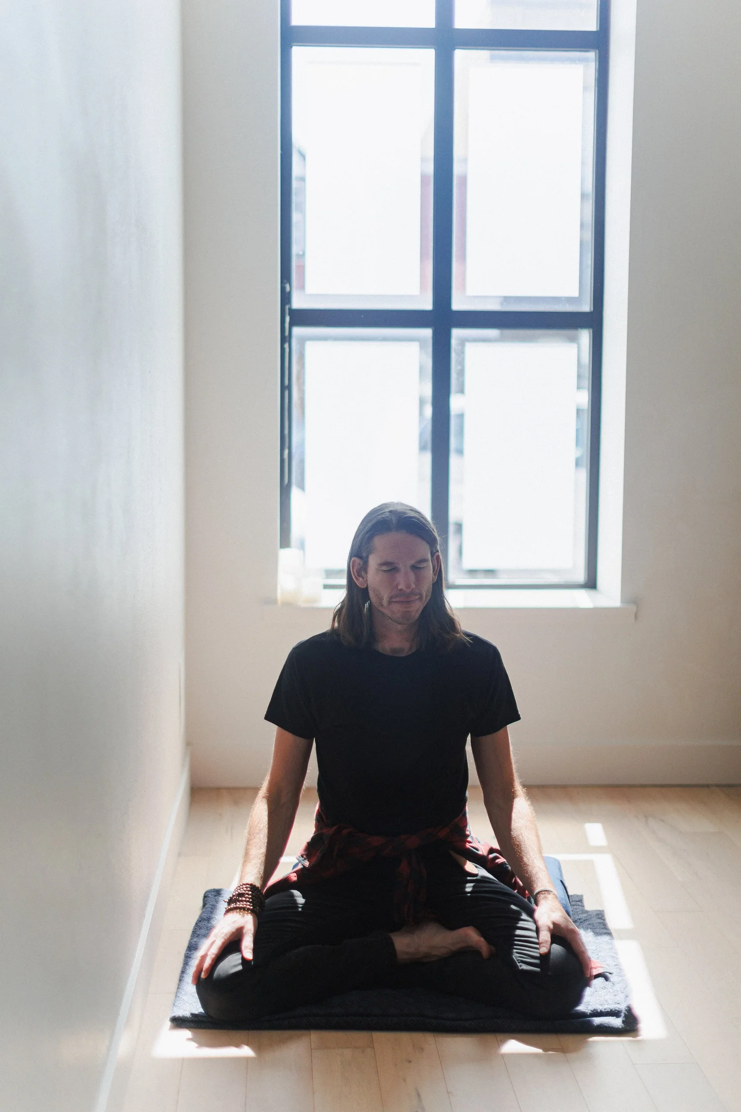 Kyle Kloostra in seated meditation by the studio window