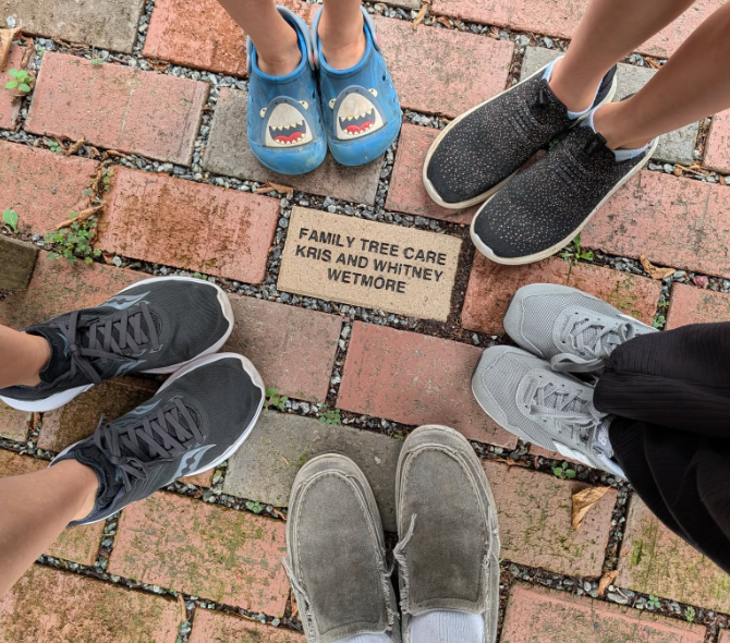 Five children wearing sneakers standing on a brick pathway around a commemorative plaque for Kris and Whitney Wetmore.