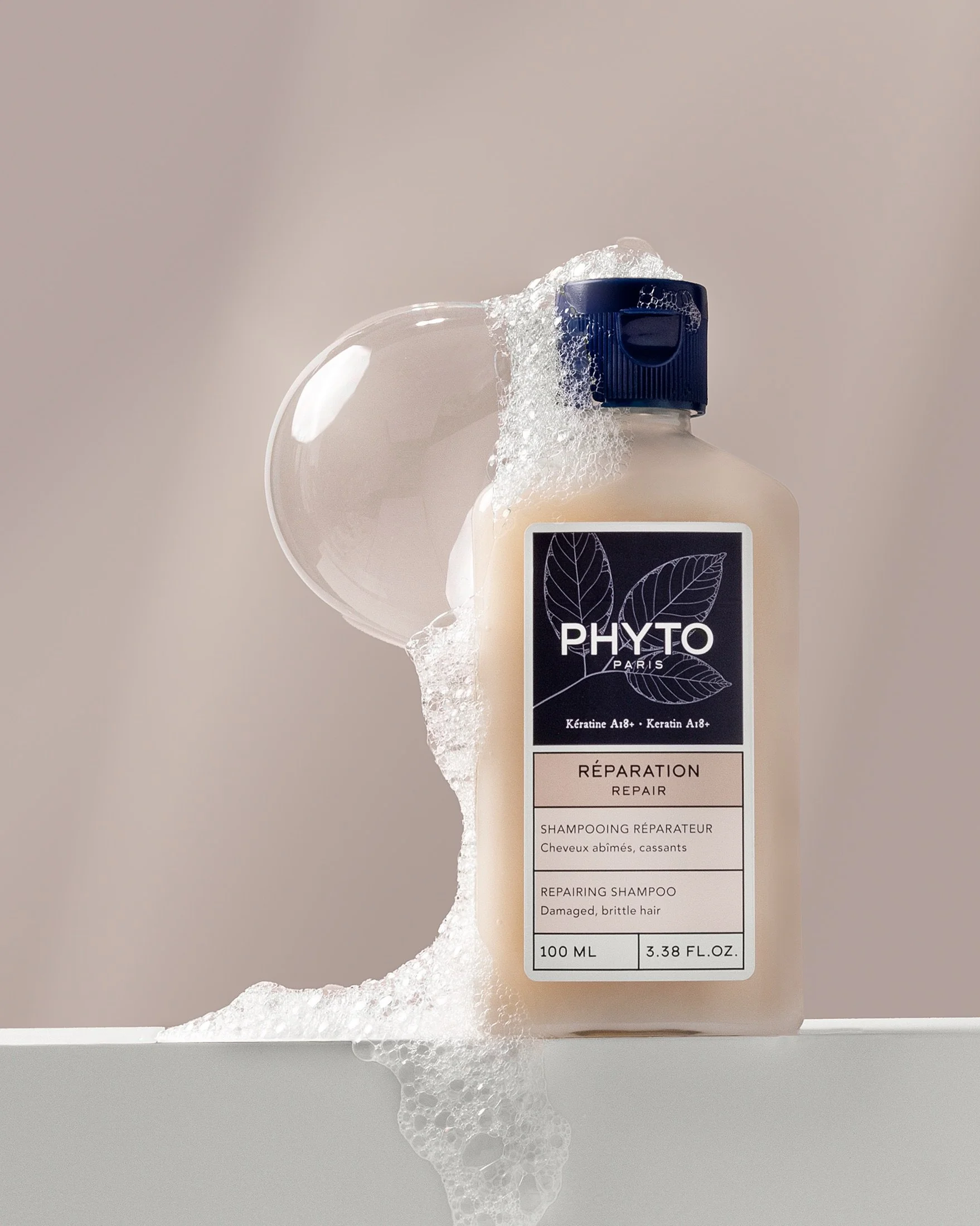 Close-up of shampoo foam and bubbles in soft natural light, highlighting texture and movement in a minimal beauty setting.