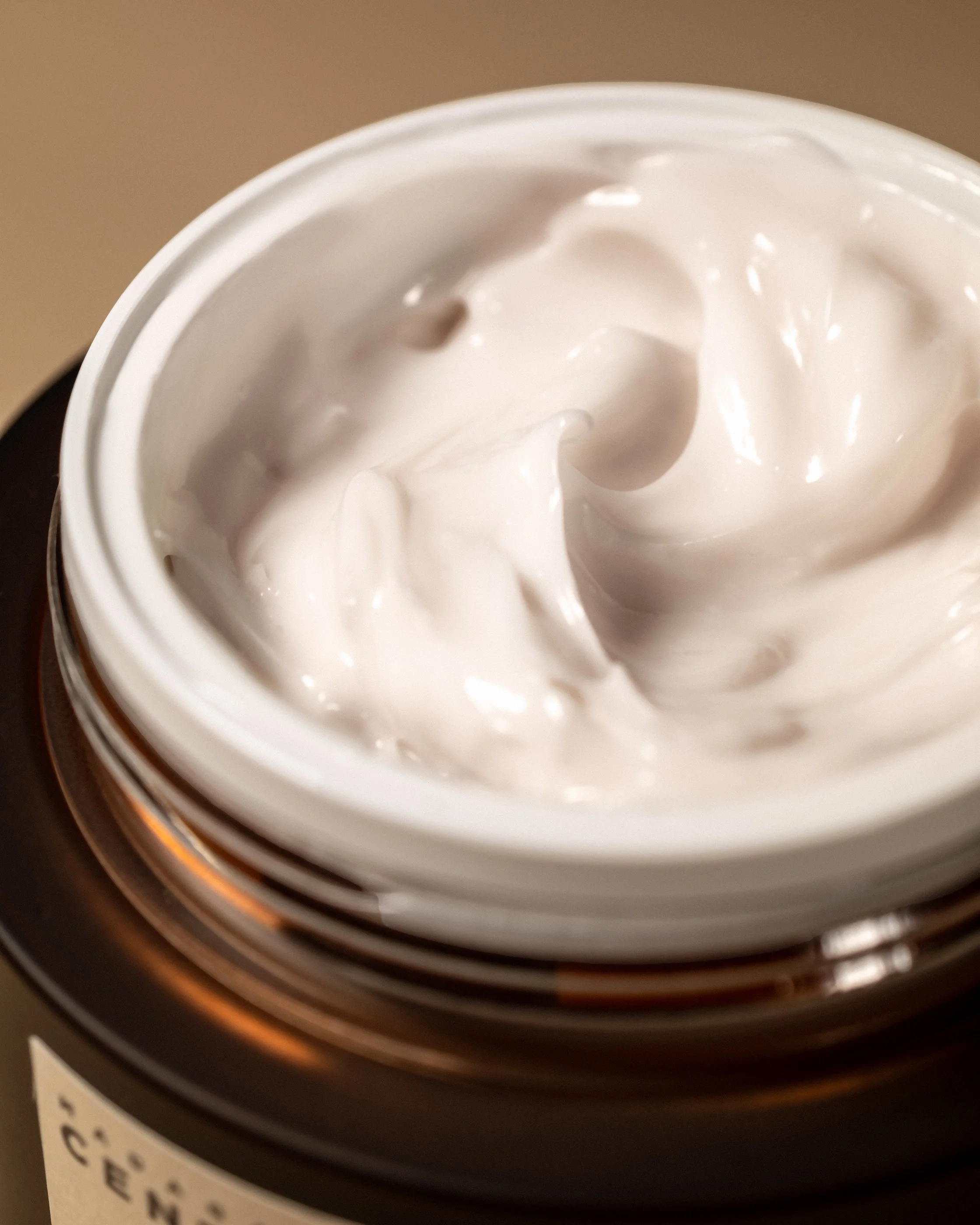 Open skincare jar filled with smooth white cream photographed in soft directional light showing realistic product consistency.