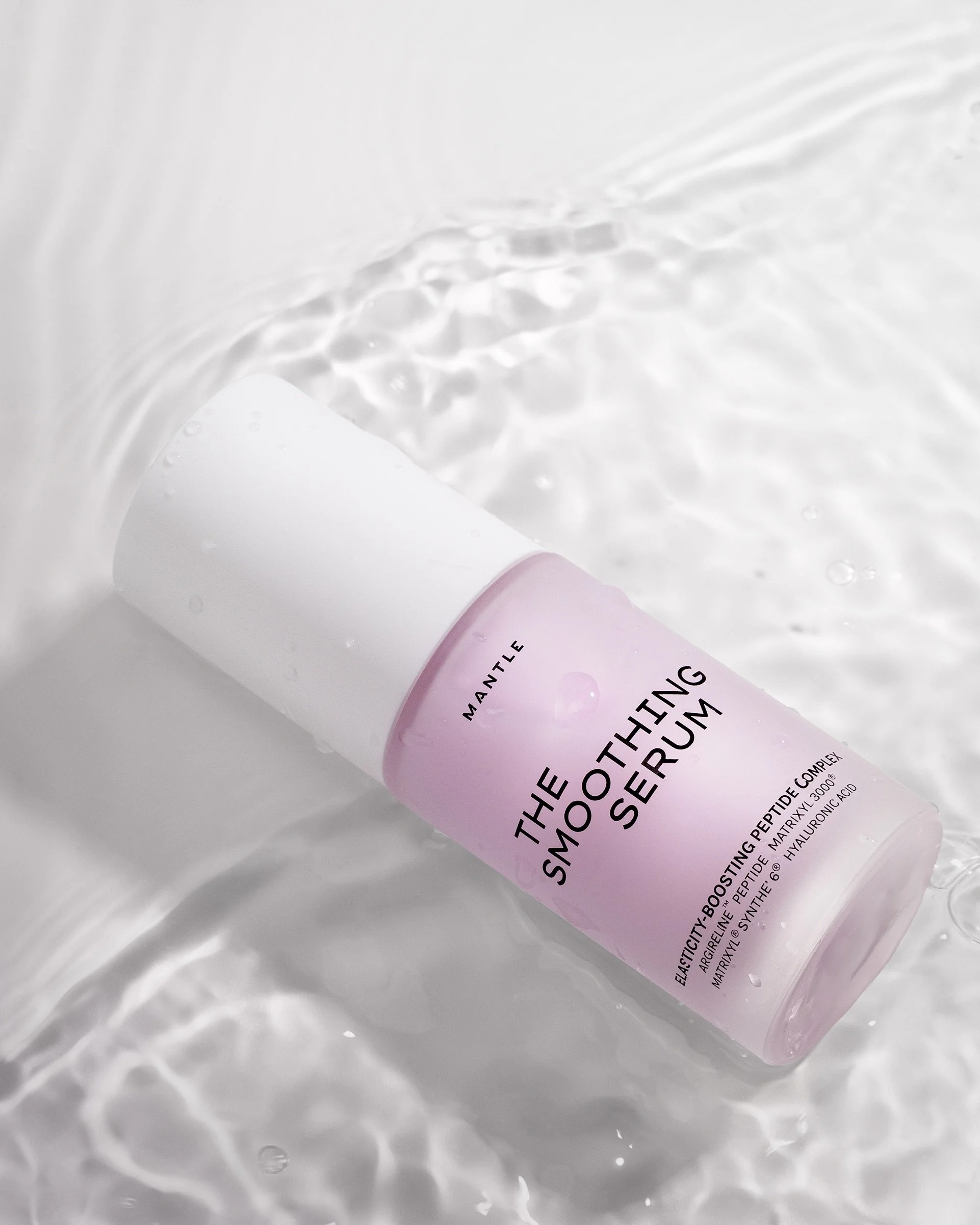 Mantle The Smoothing Serum peptide and hyaluronic acid serum bottle lying in rippling water on white background