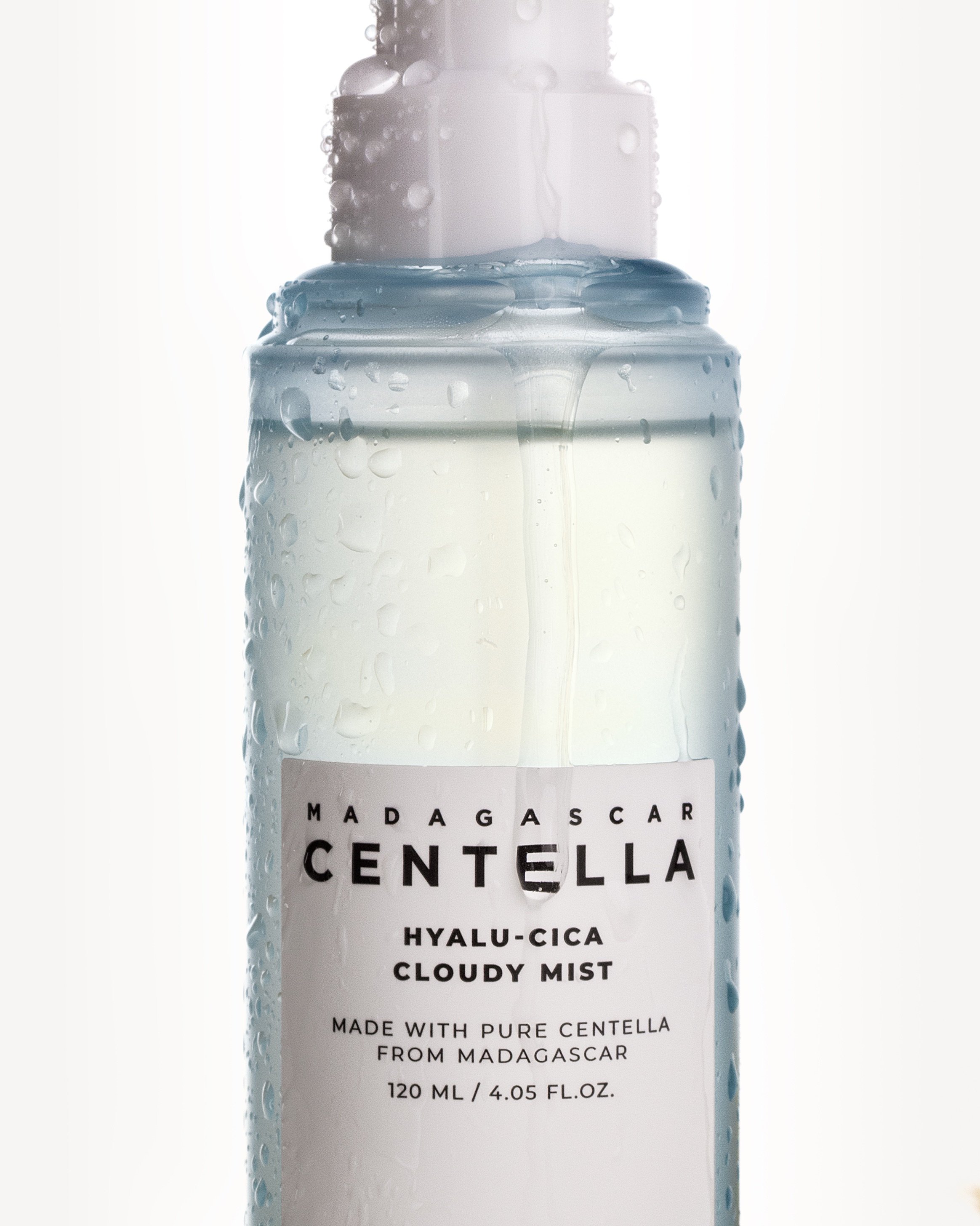 A tall bottle of Madagascar Centella Hyalu-Cica Cloudy Mist with condensation on the outside, labeled with product details, and a white background.