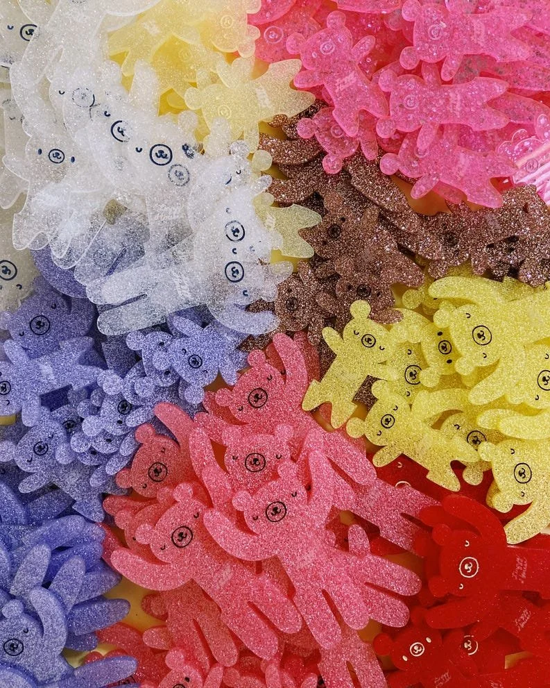 Colorful glitter foam cutouts of bears, unicorns, and other animal shapes in white, yellow, pink, purple, brown, and red, scattered densely across the image.