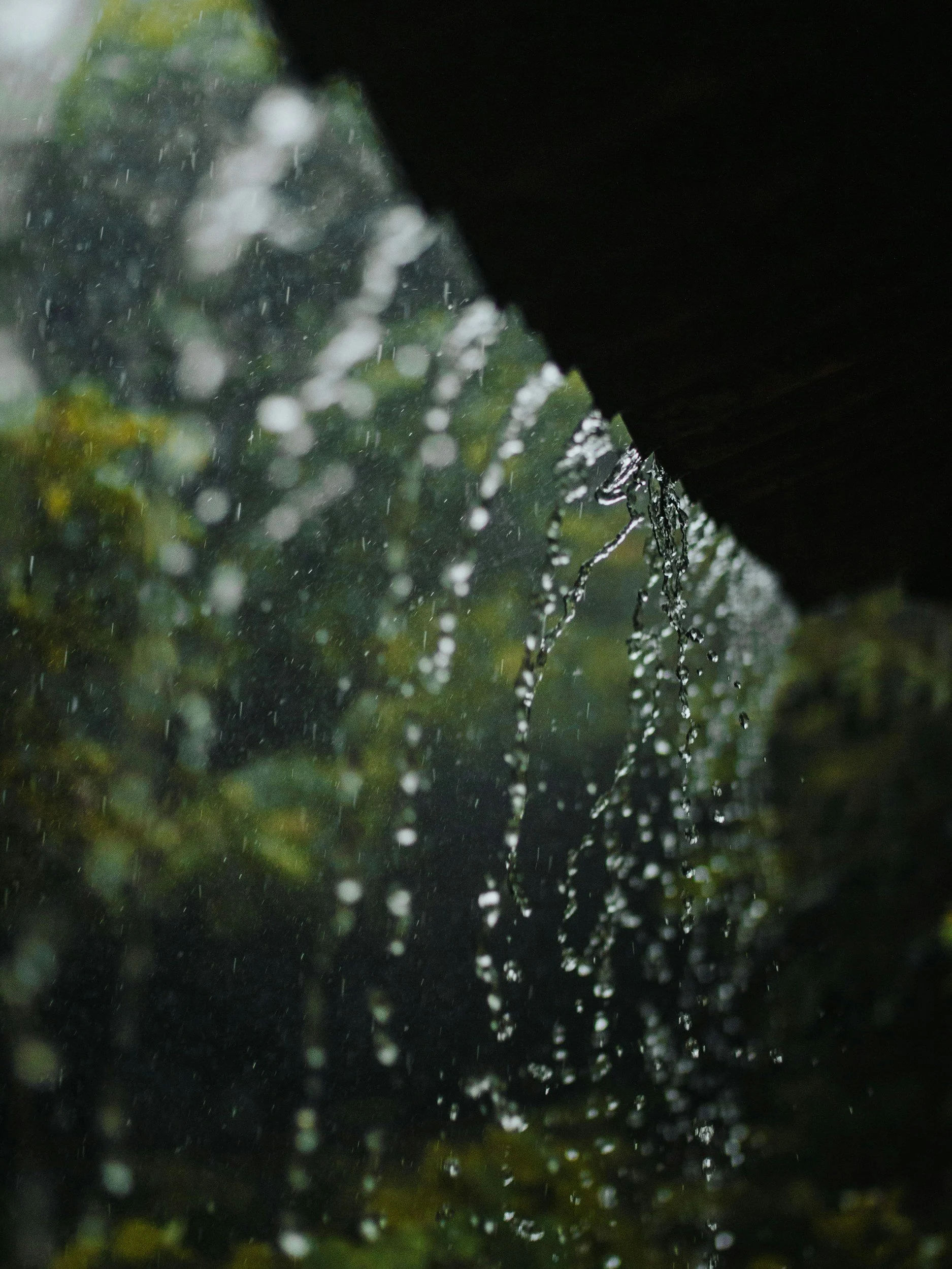 Rainwater pouring off the side of a building while it's still raining.
