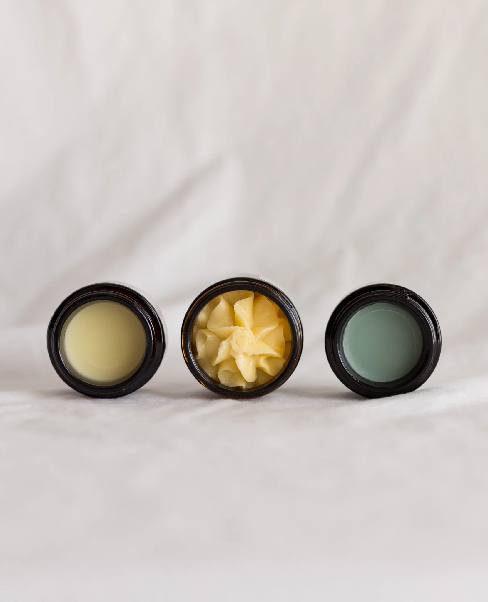 Open jar of Meadowlark Made tallow facial balms showing the textures and colors in the three jars
