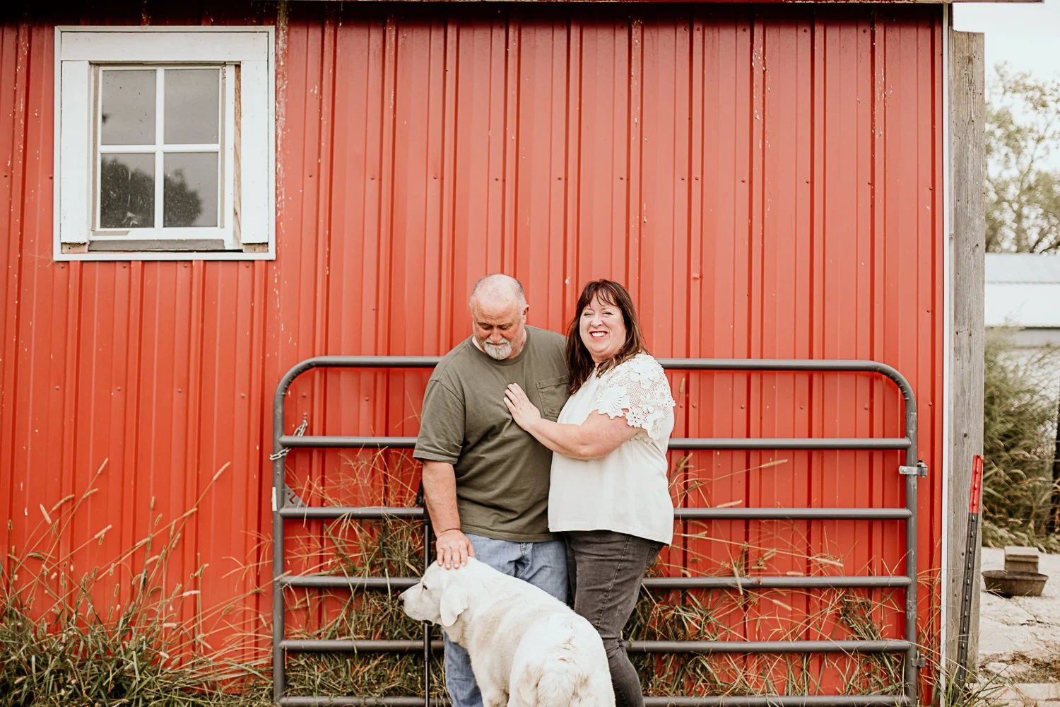 Steve and Heather Scar, owners and farmers at Meadowlark Farm, standing in front of a red barn