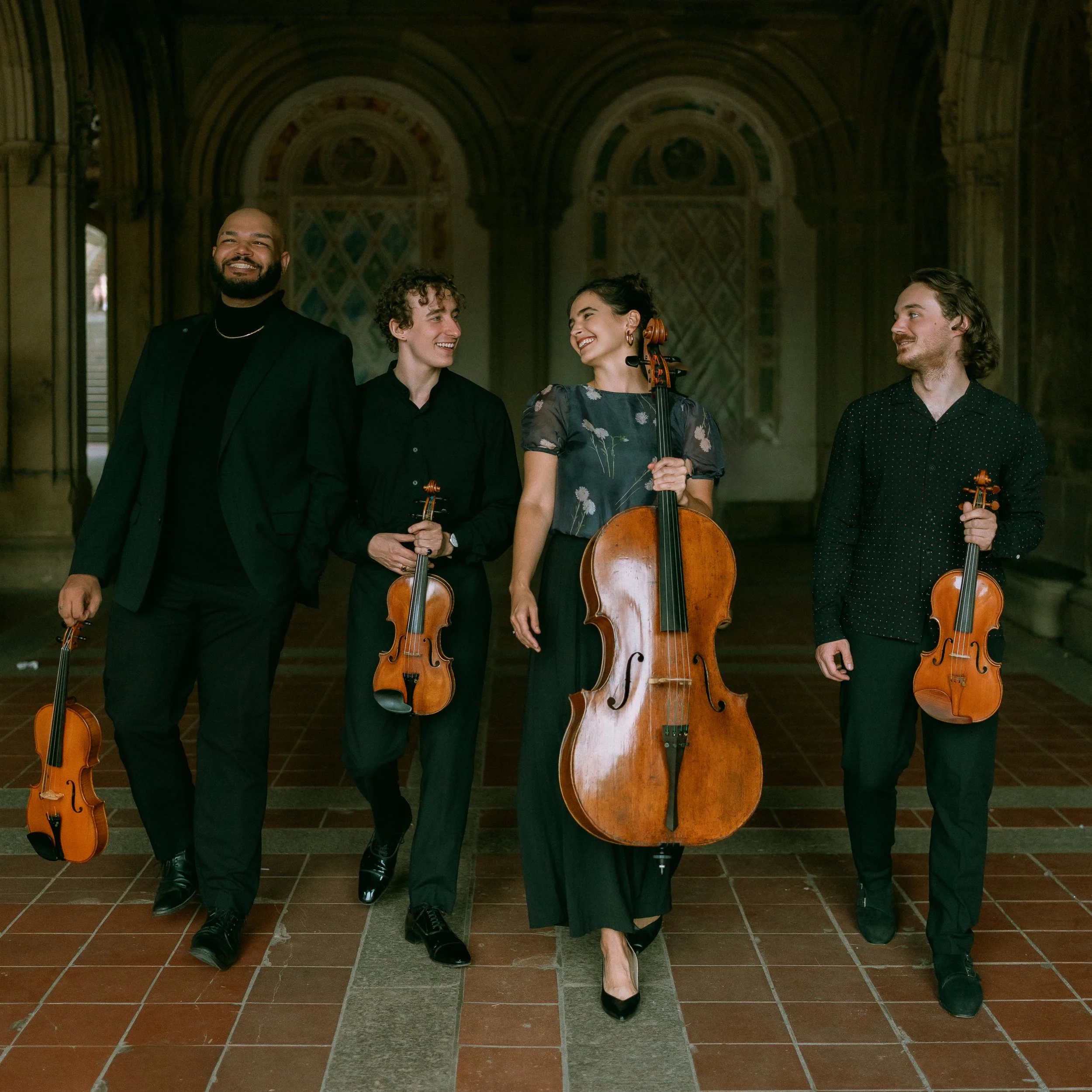 Isidore String Quartet walking and smiling with instruments.