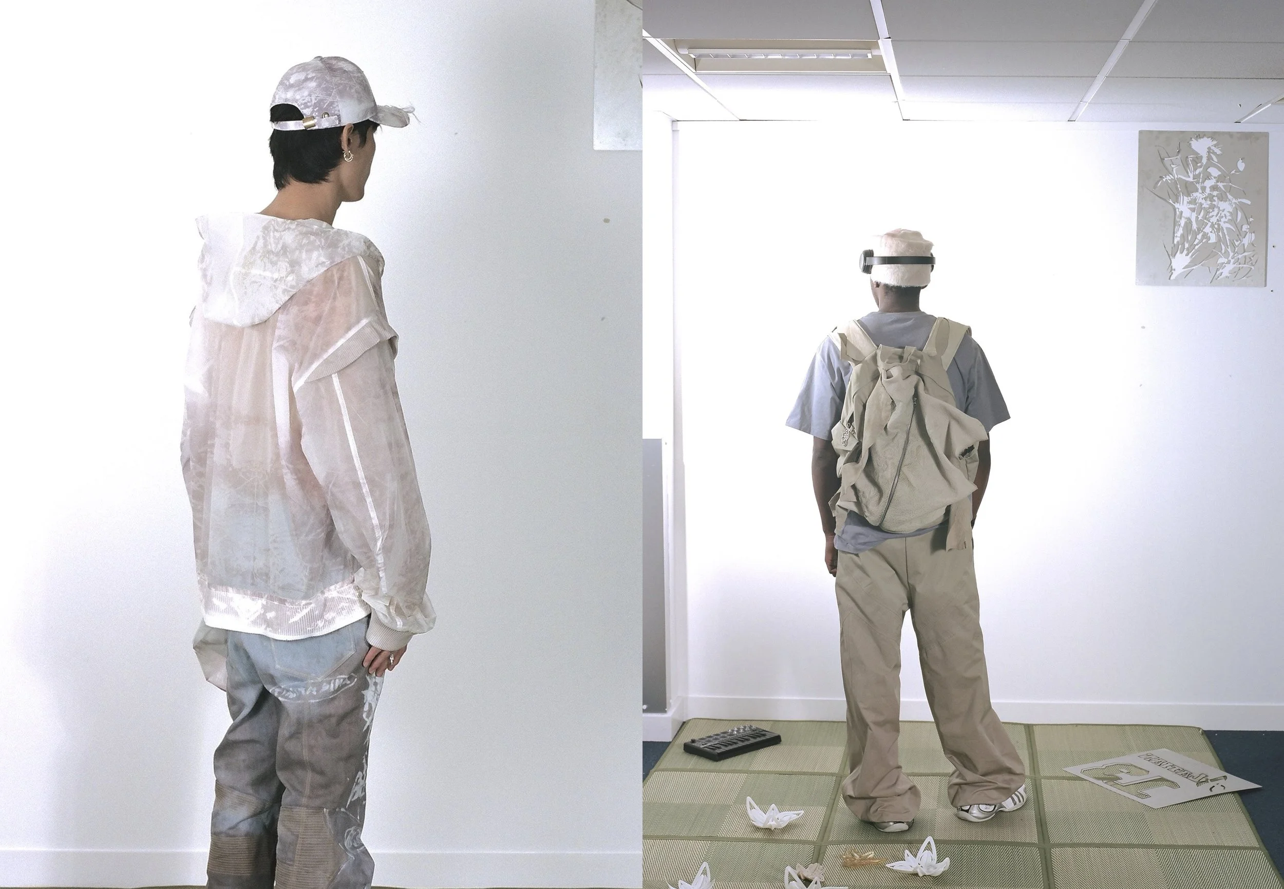 Two people facing away wearing light-colored clothing and hats, one with a backpack, standing indoors against a white background. The second person stands on a mat with some objects on the floor, including white folded paper-like items and a keyboard